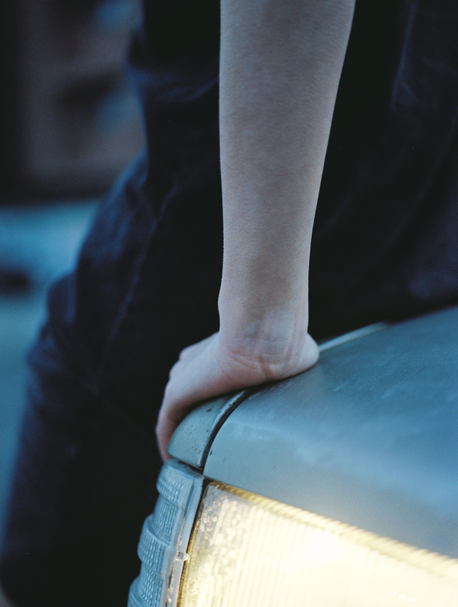 a close up of a person's hand, leaning on a car bonnet