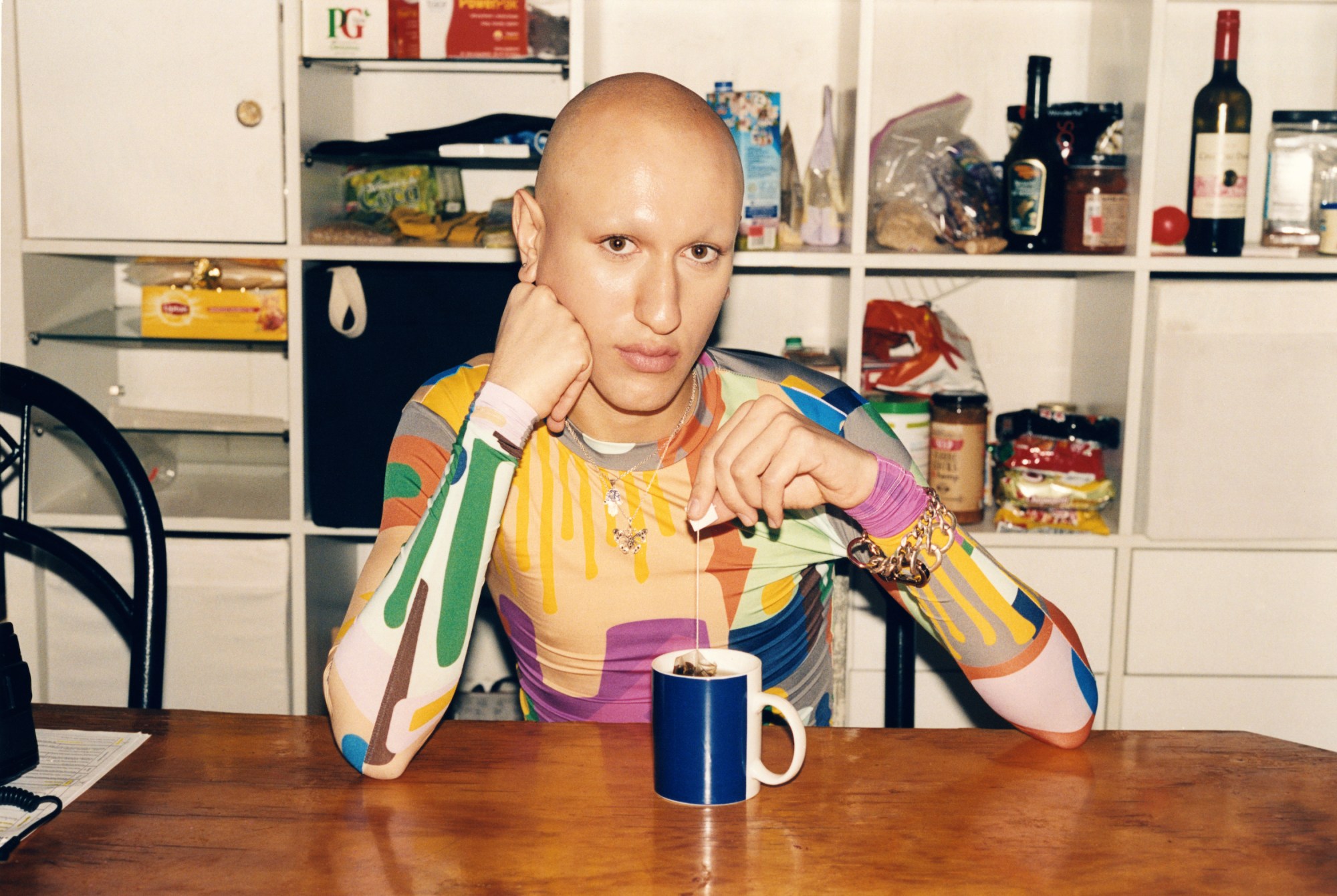 ciggaria sitting at the kitchen table with tea and a bright colored shirt on