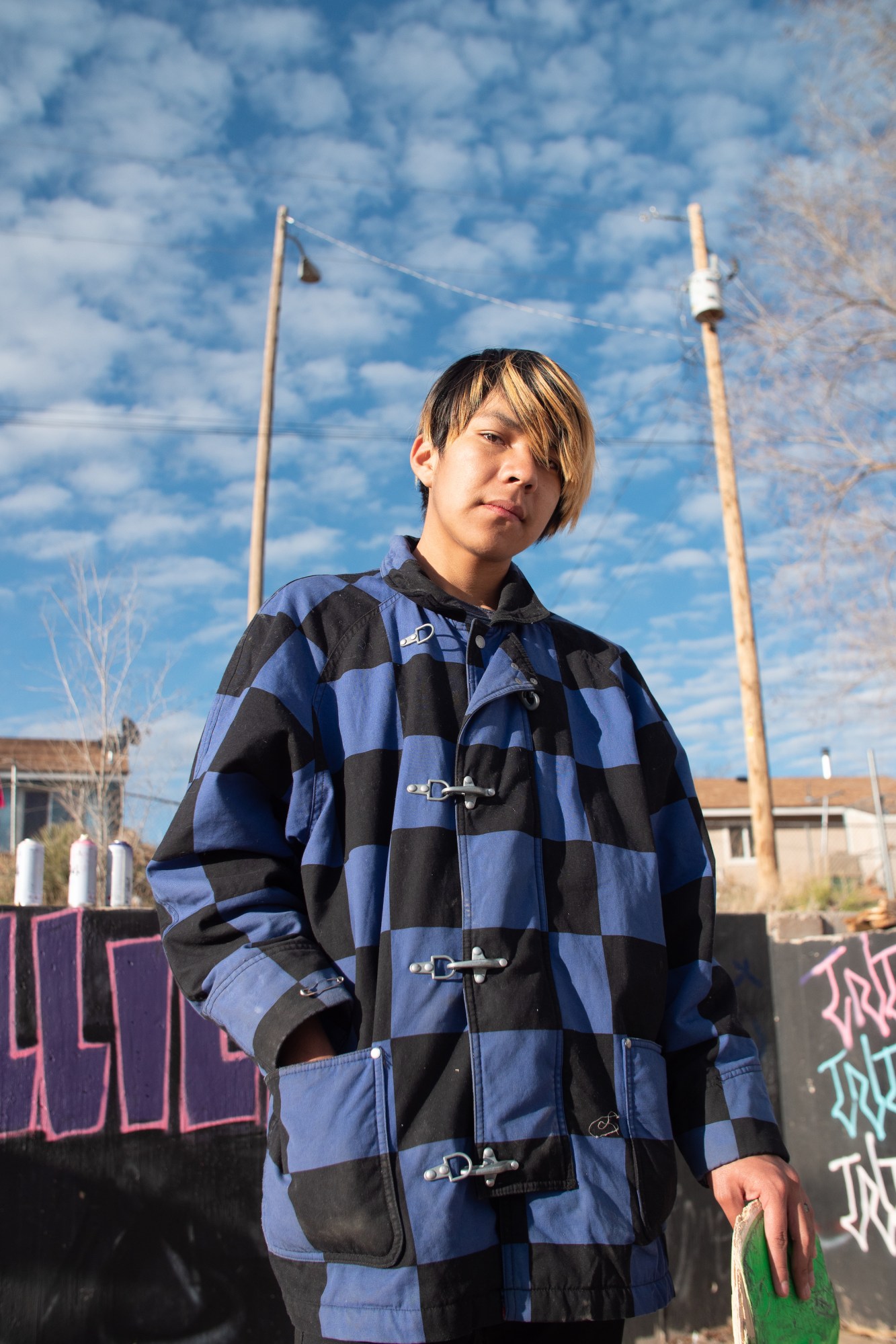 a young skater in a patchwork jacket with his hand in his pocket