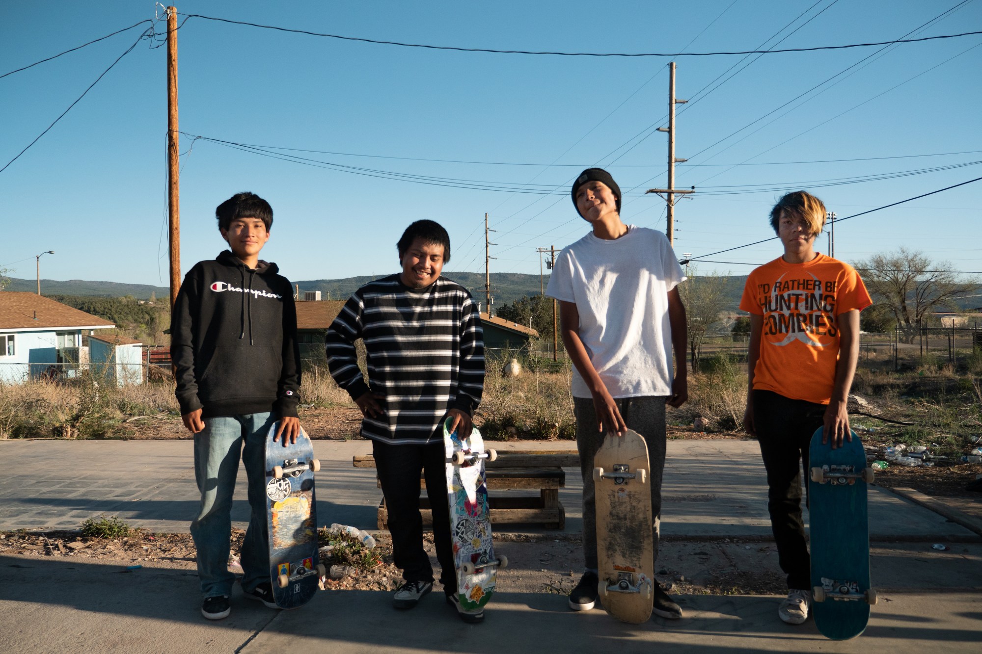 four young native skaters holding up their boards