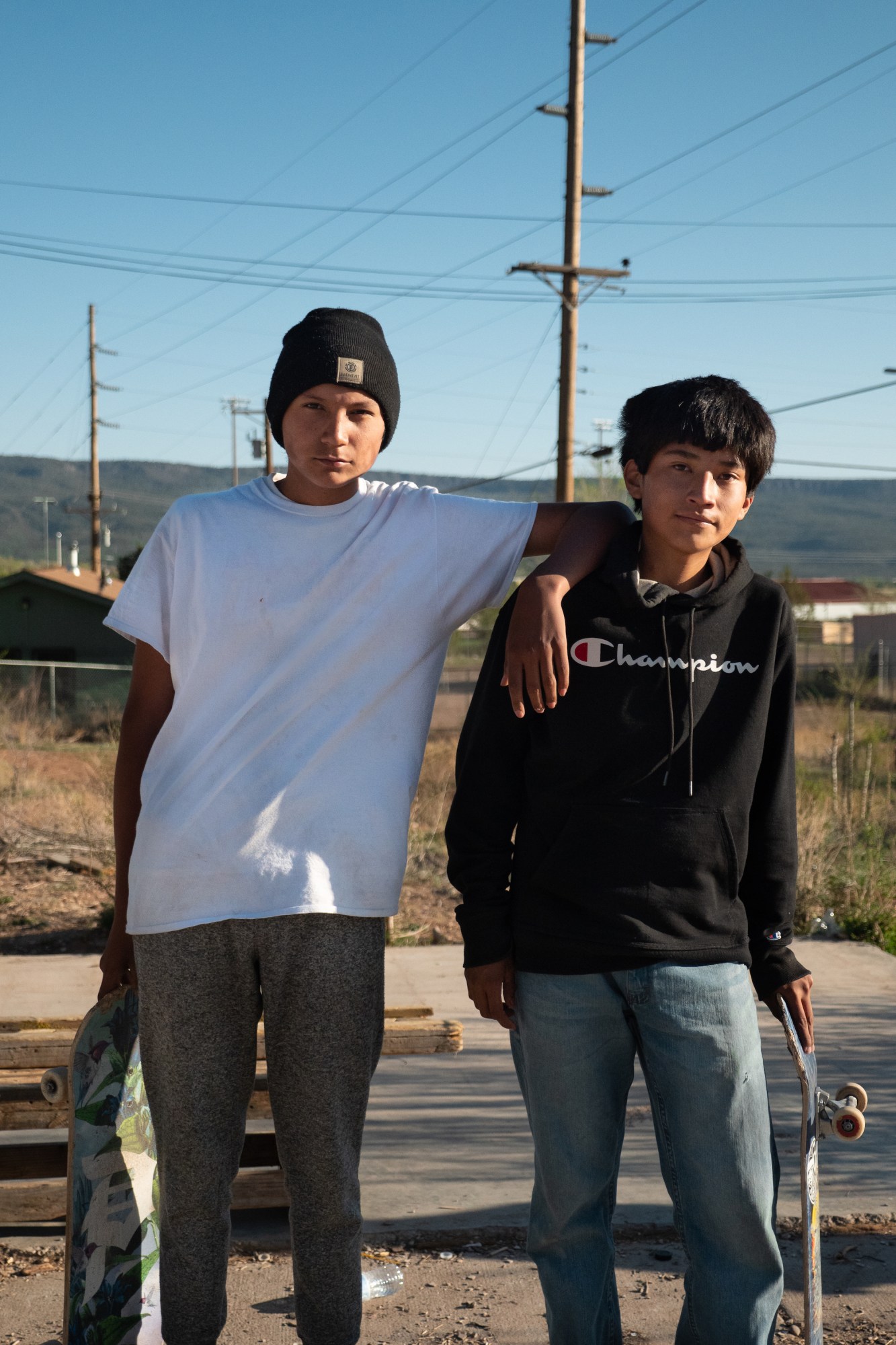 two young native skaters standing side by side with their boards