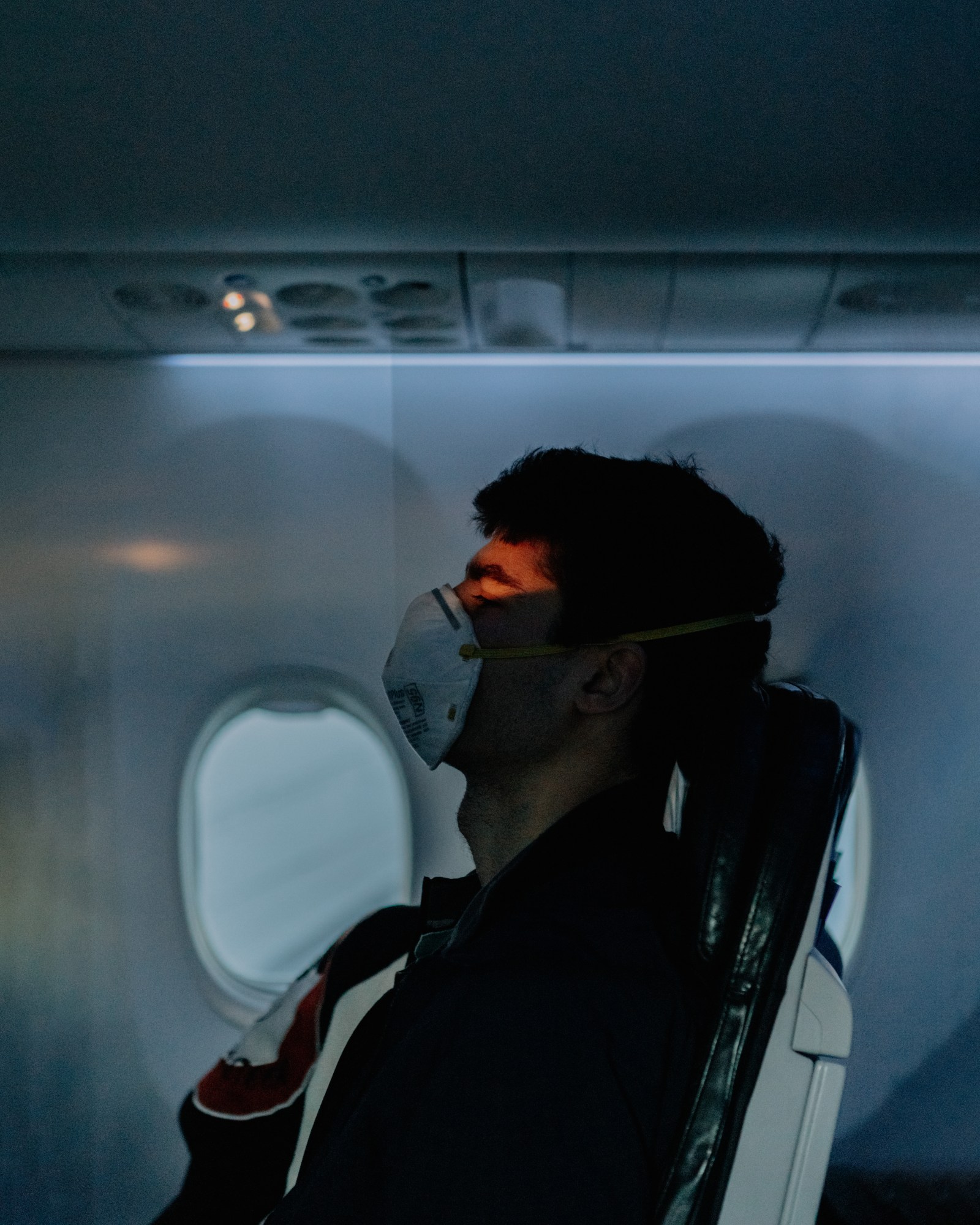 a sleeping man wearing a mask on a flight