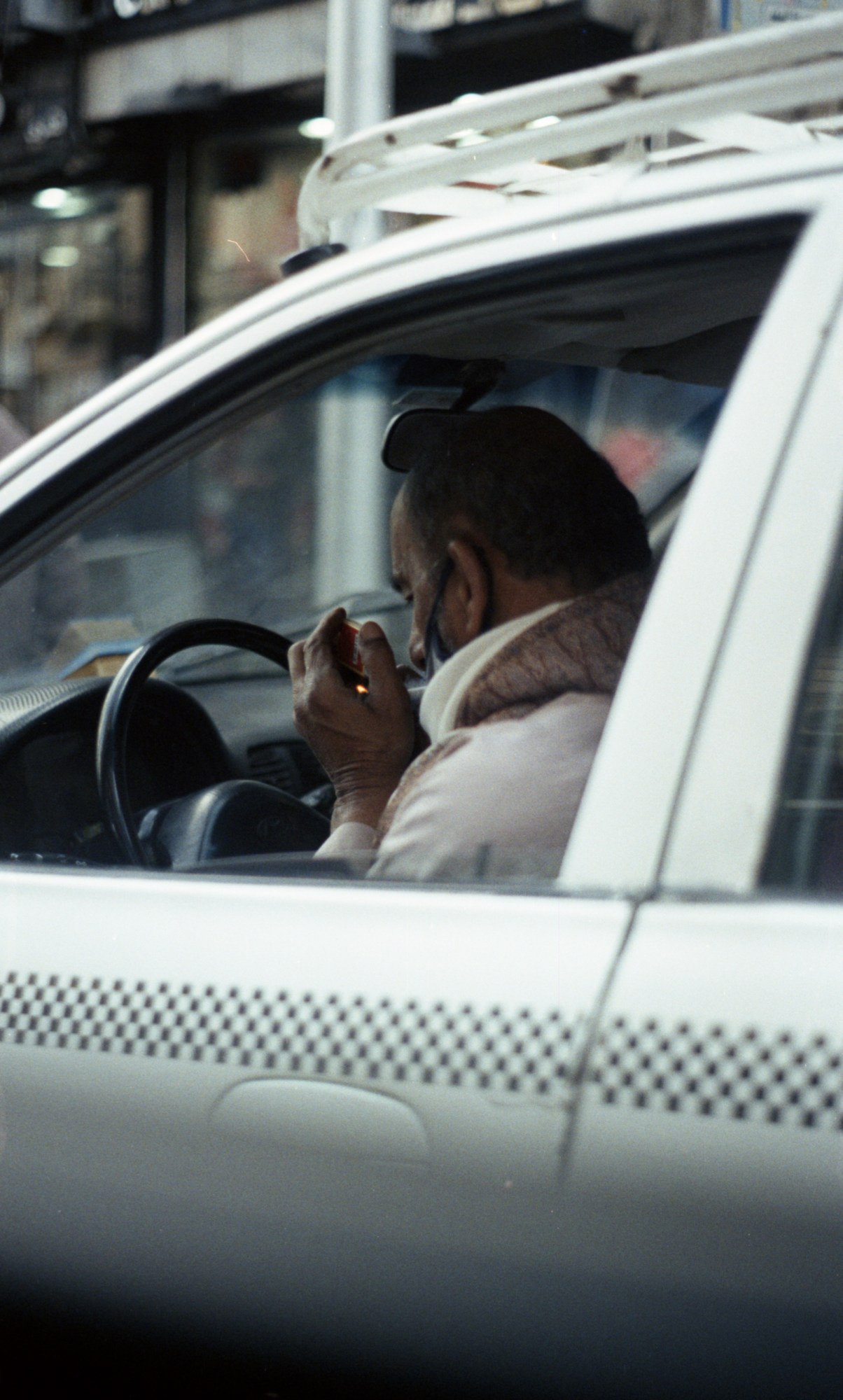 a man driving a taxi lights a cigarette