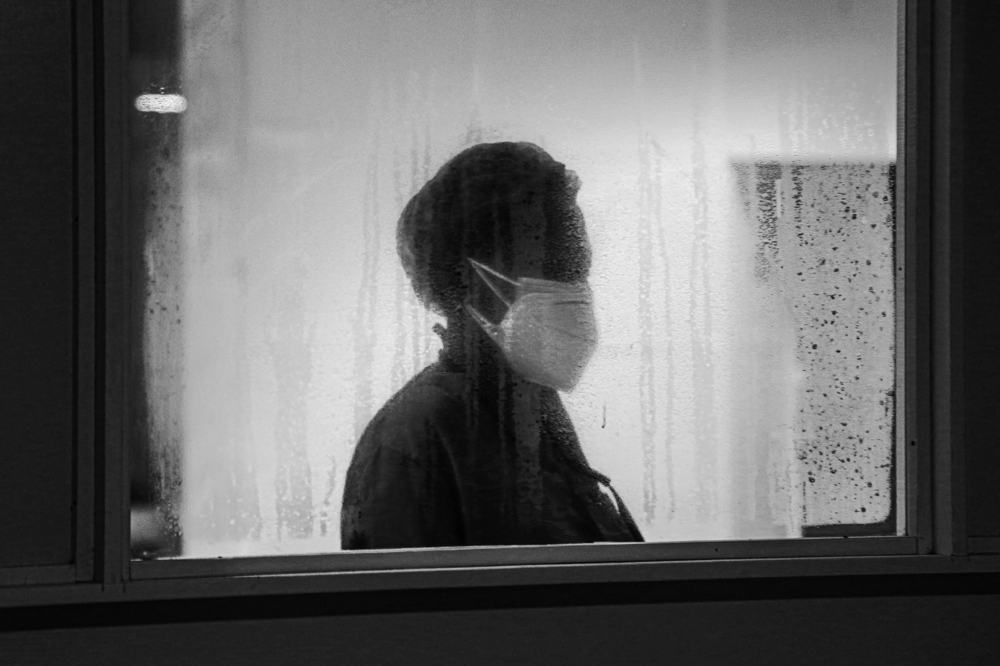 a nurse wearing a mask, taken through a steamed-up window