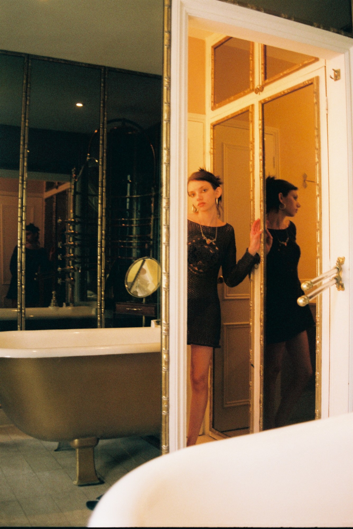 a woman in a dress standing in the doorway of a fancy bathroom