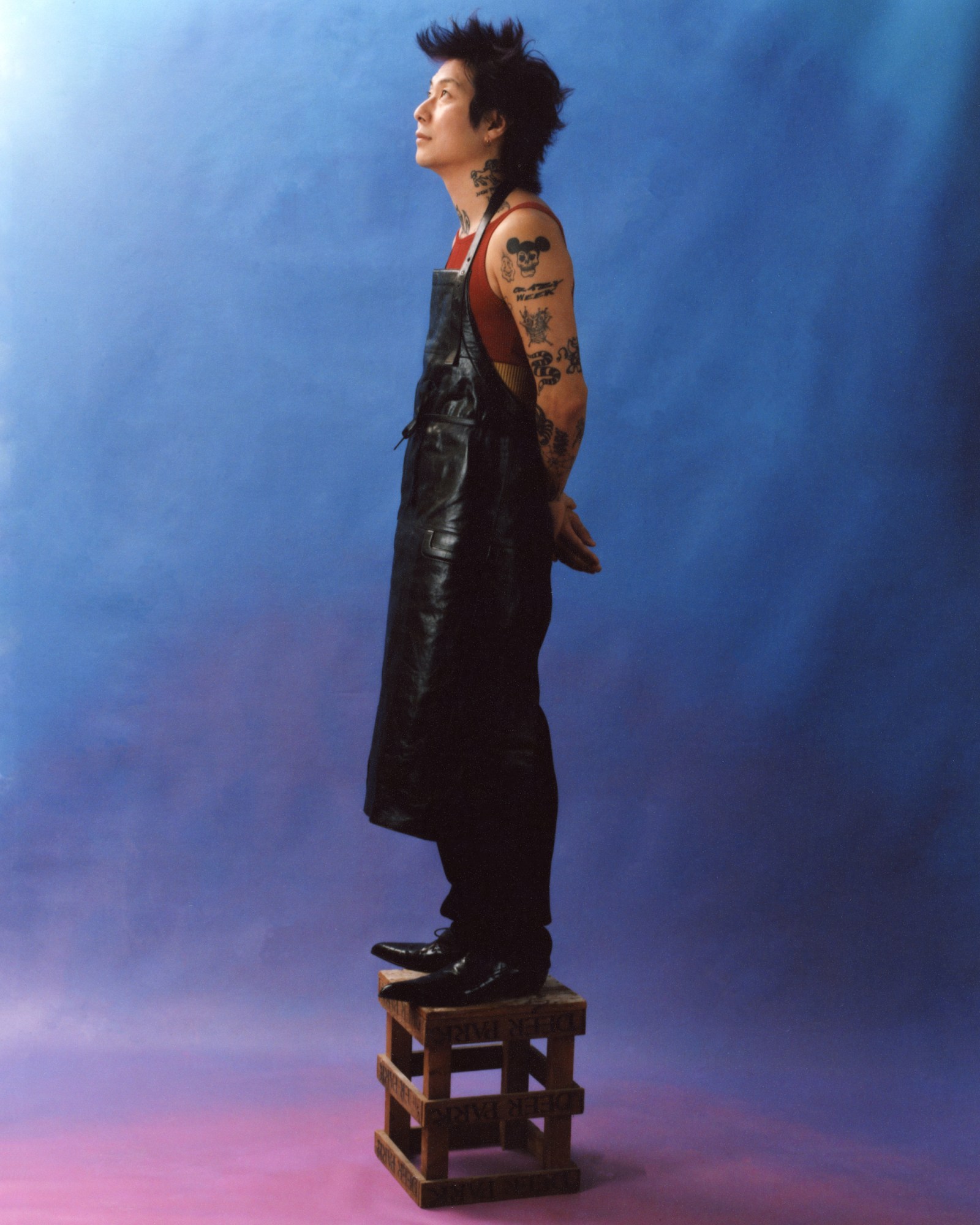 Danny bowien standing on top of a crate in a leather apron