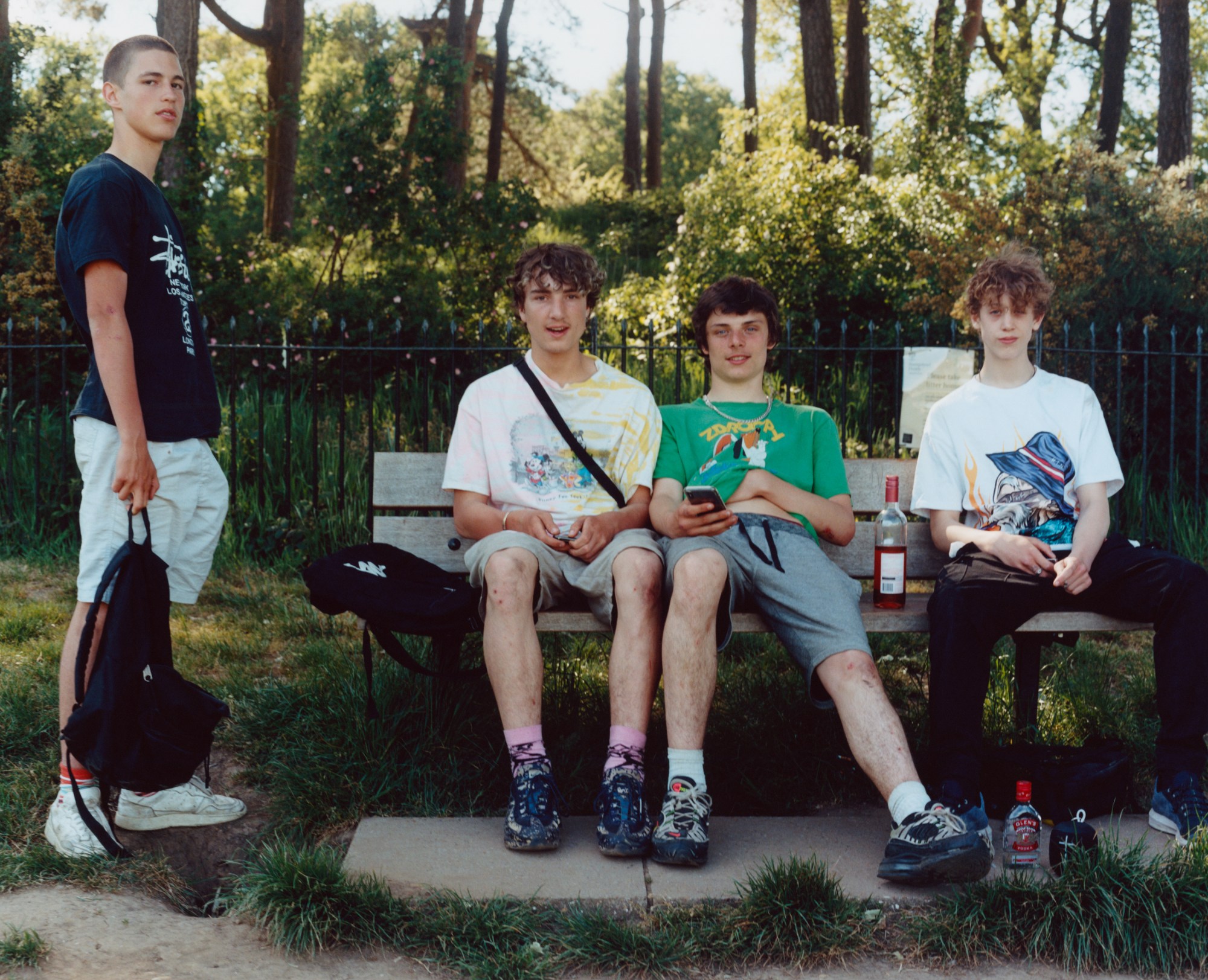 four boys in the park, three of whom are sitting on a bench