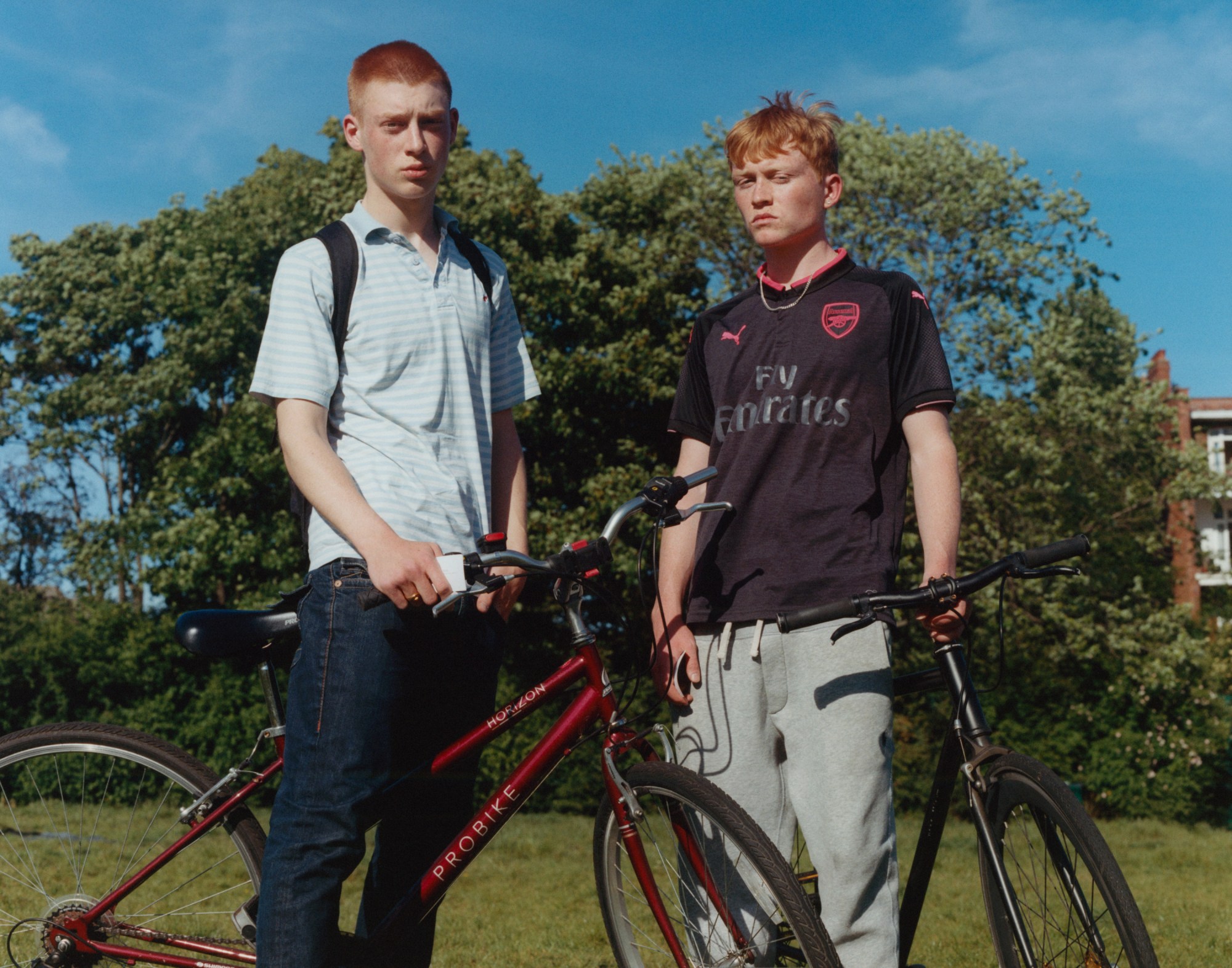 two boys with red hair stand with their bikes