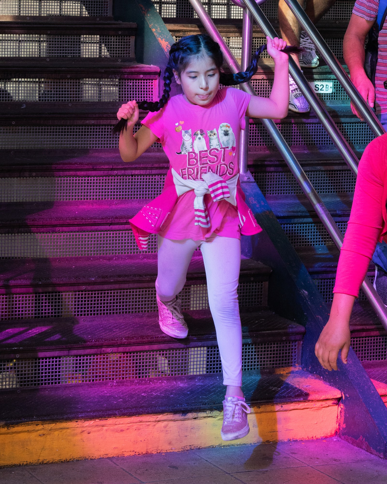 a young girl with a pink t-shirt that says best friends walks down the steps of a new york subway station