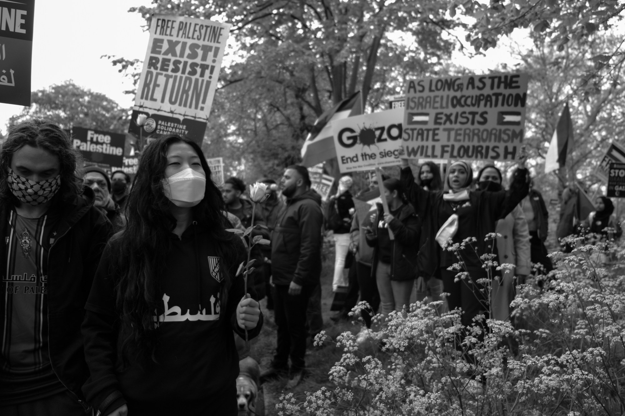 a group of people march holding 'Free Palestine' banners and flowers