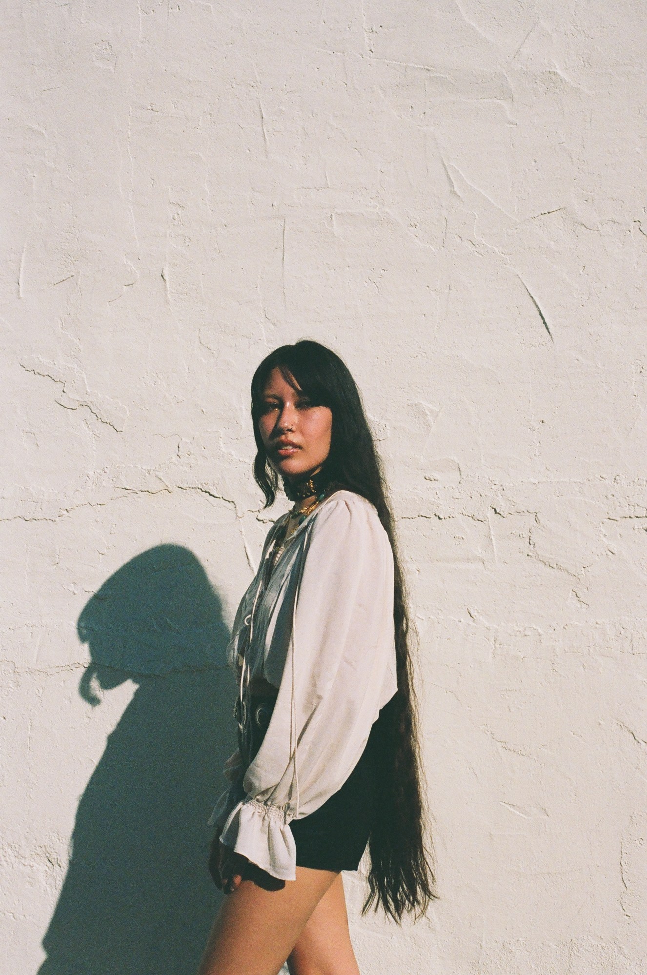 sonya thorbjornsen standing sideways in front of a white wall