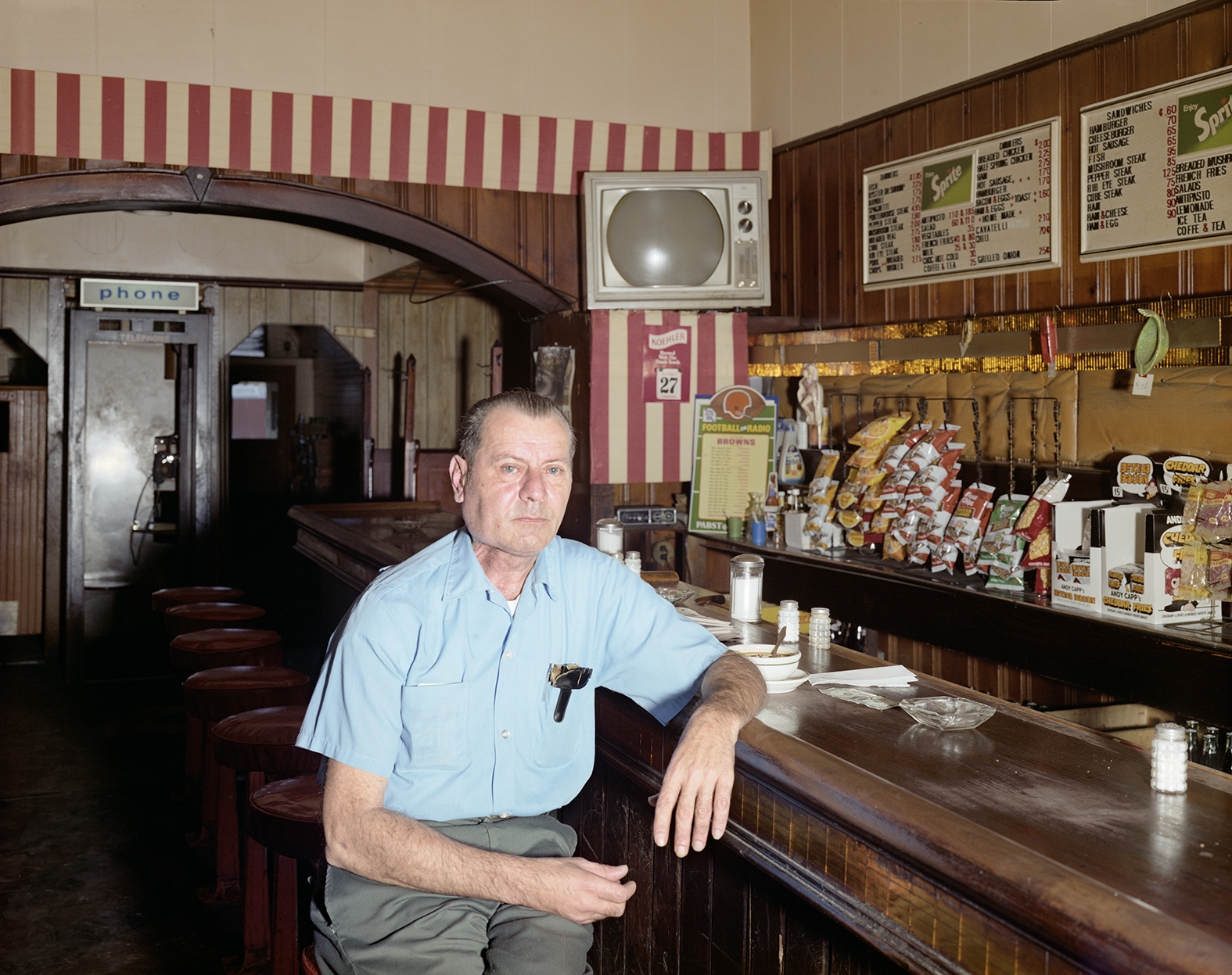 A man wearing a blue shirt leans against a bar at Eddie's Wagon Wheel, in 1977.