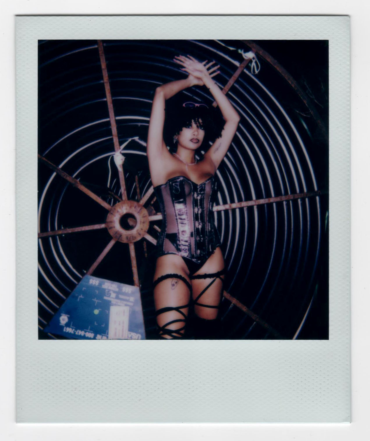 marceline steel in a bustier standing with her arms up in front of a fan