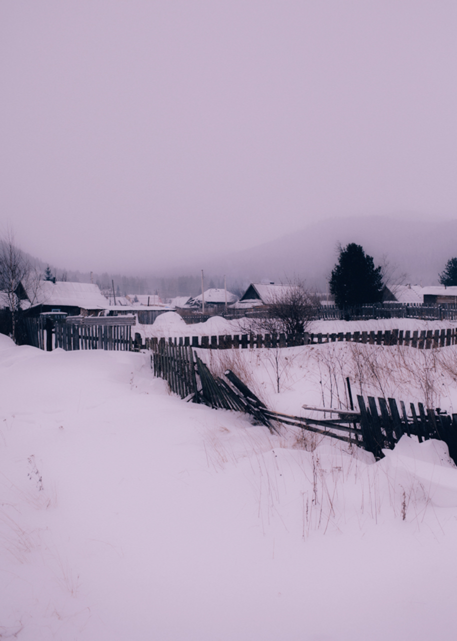 a snowy siberian town, with broken fences and one story houses