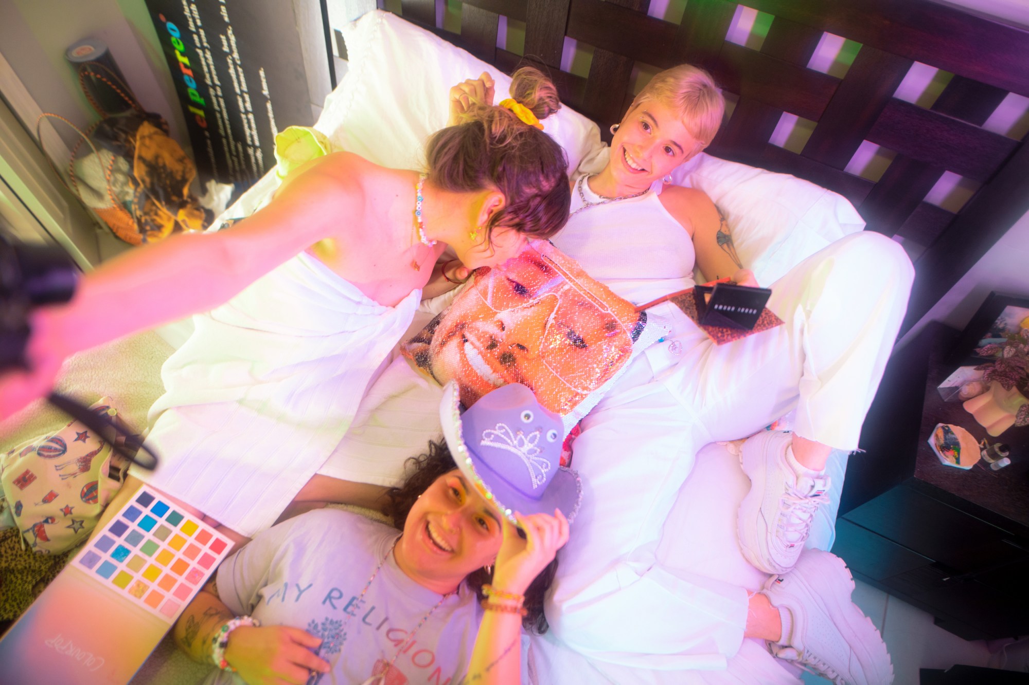 three girls lying in a bed with a bad bunny pillow