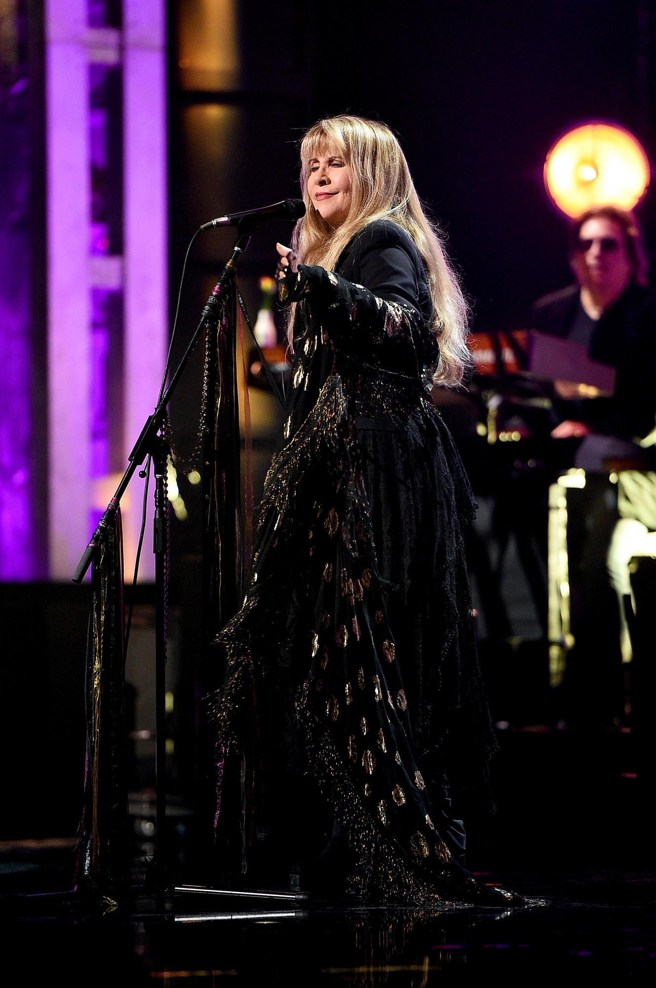 stevie nicks singing and gesturing to the crowd performing at the rock and roll hall of fame