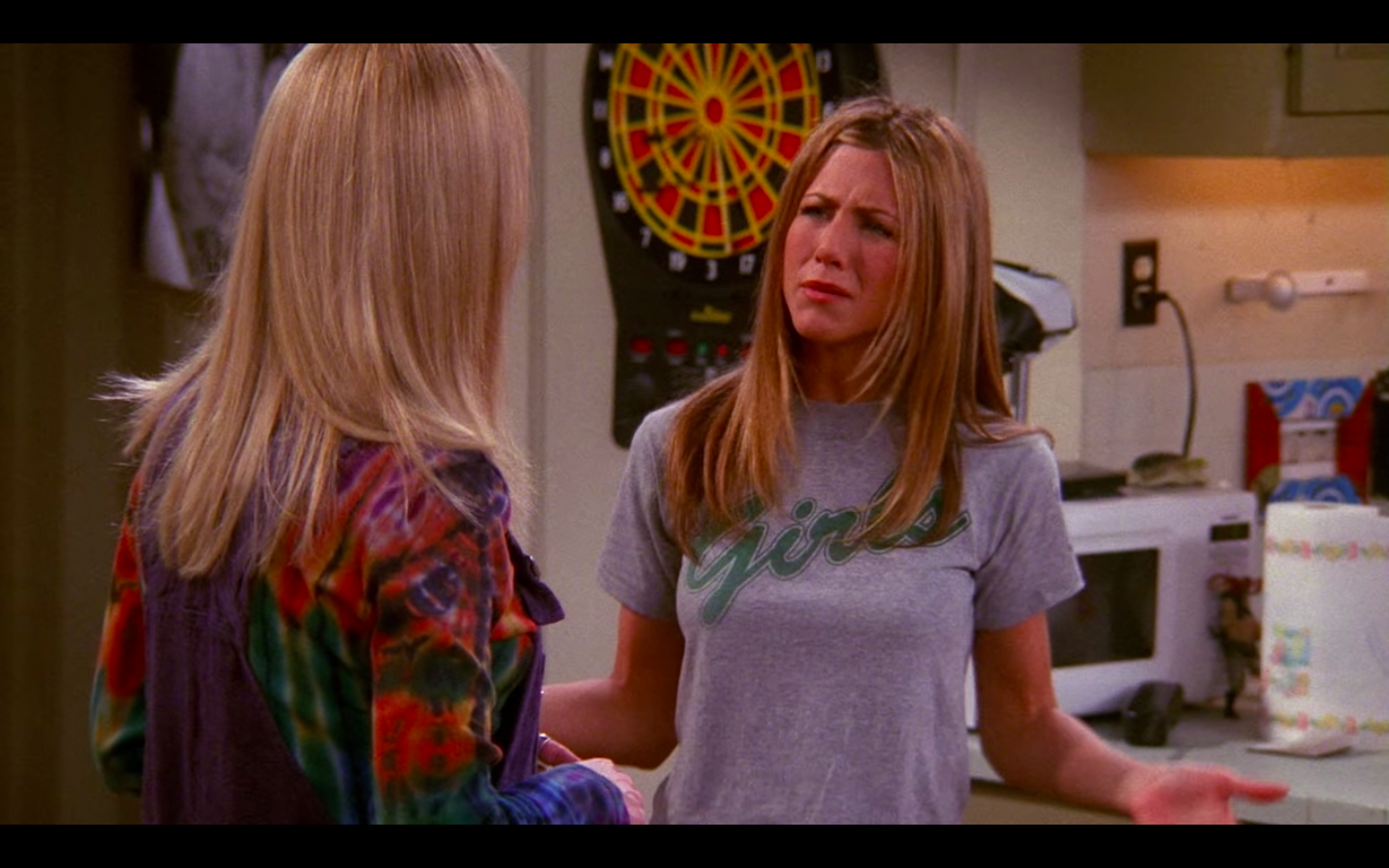 Jennifer Aniston as Rachel Green in Friends wearing a grey t-shirt emblazoned with 'Girls' across the chest in green.