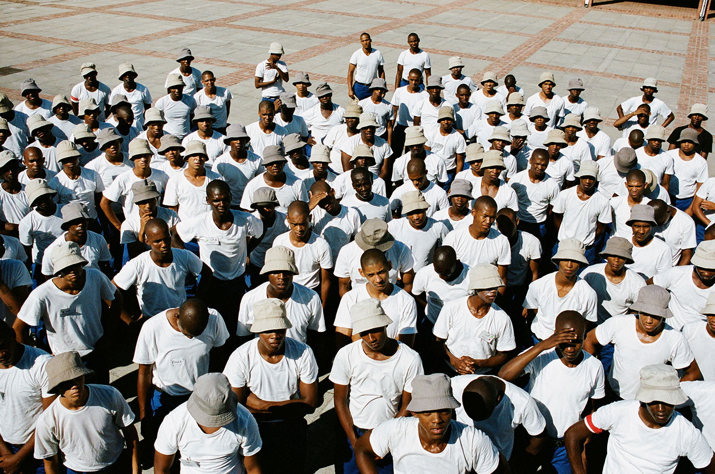 a crowd of men in white t-shirts and grey bucket hats