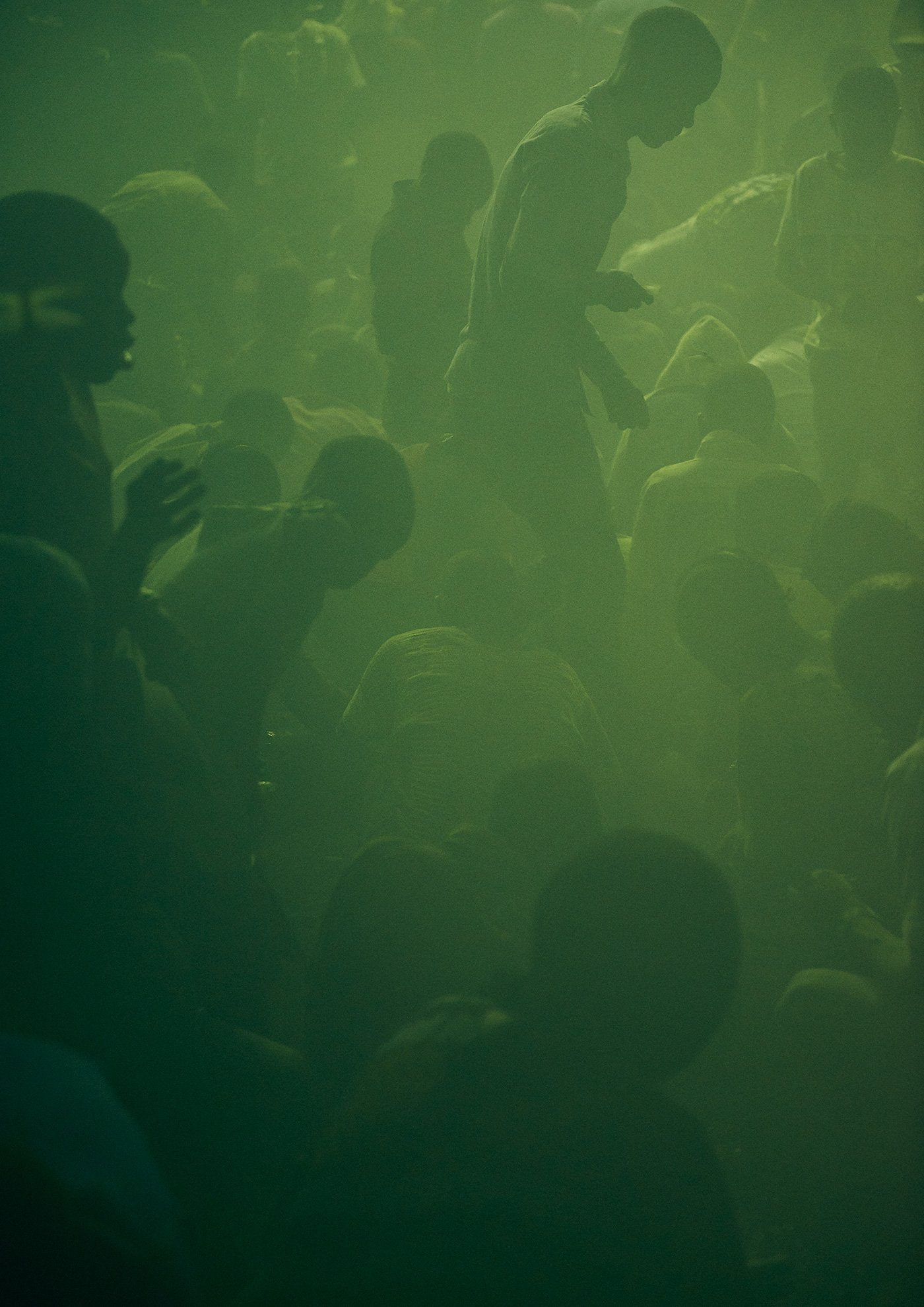 a hazy green mass of bodies, some sat others stood up