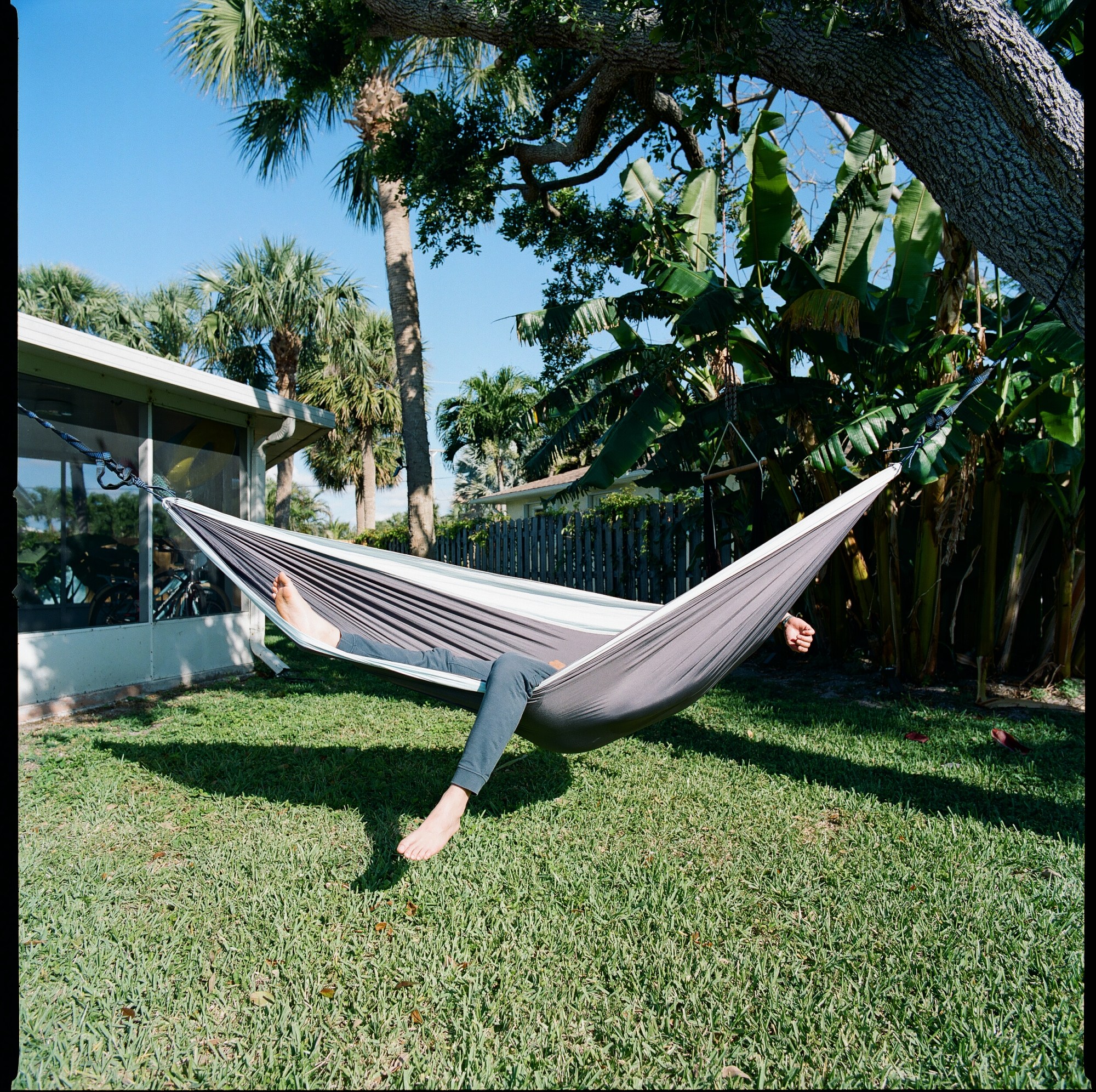 someone lounging on a hammock in their garden, legs sticking out.