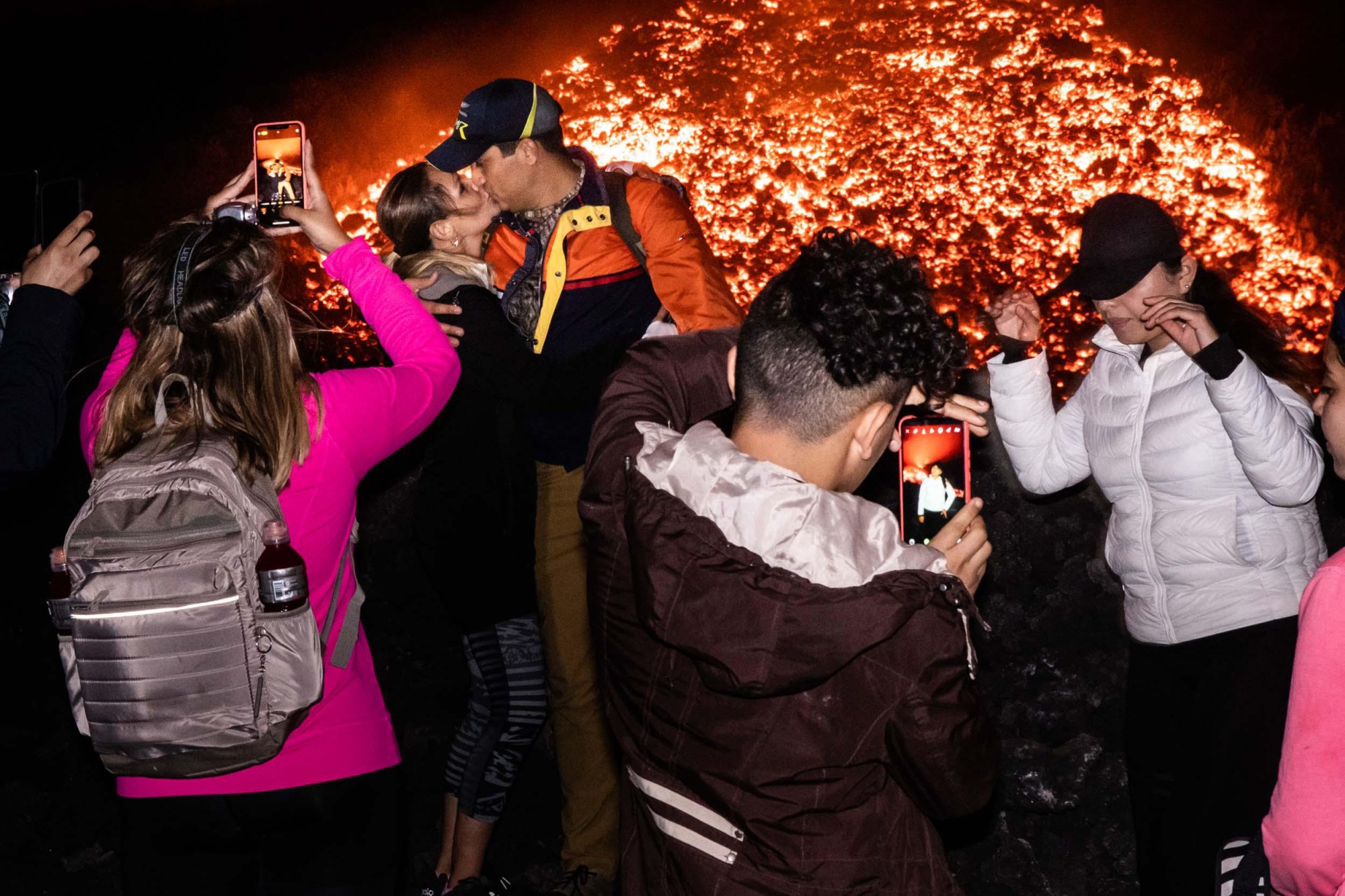 A couple kissing and others taking selfies and photos in front of an exploding volcano in Guatemala.