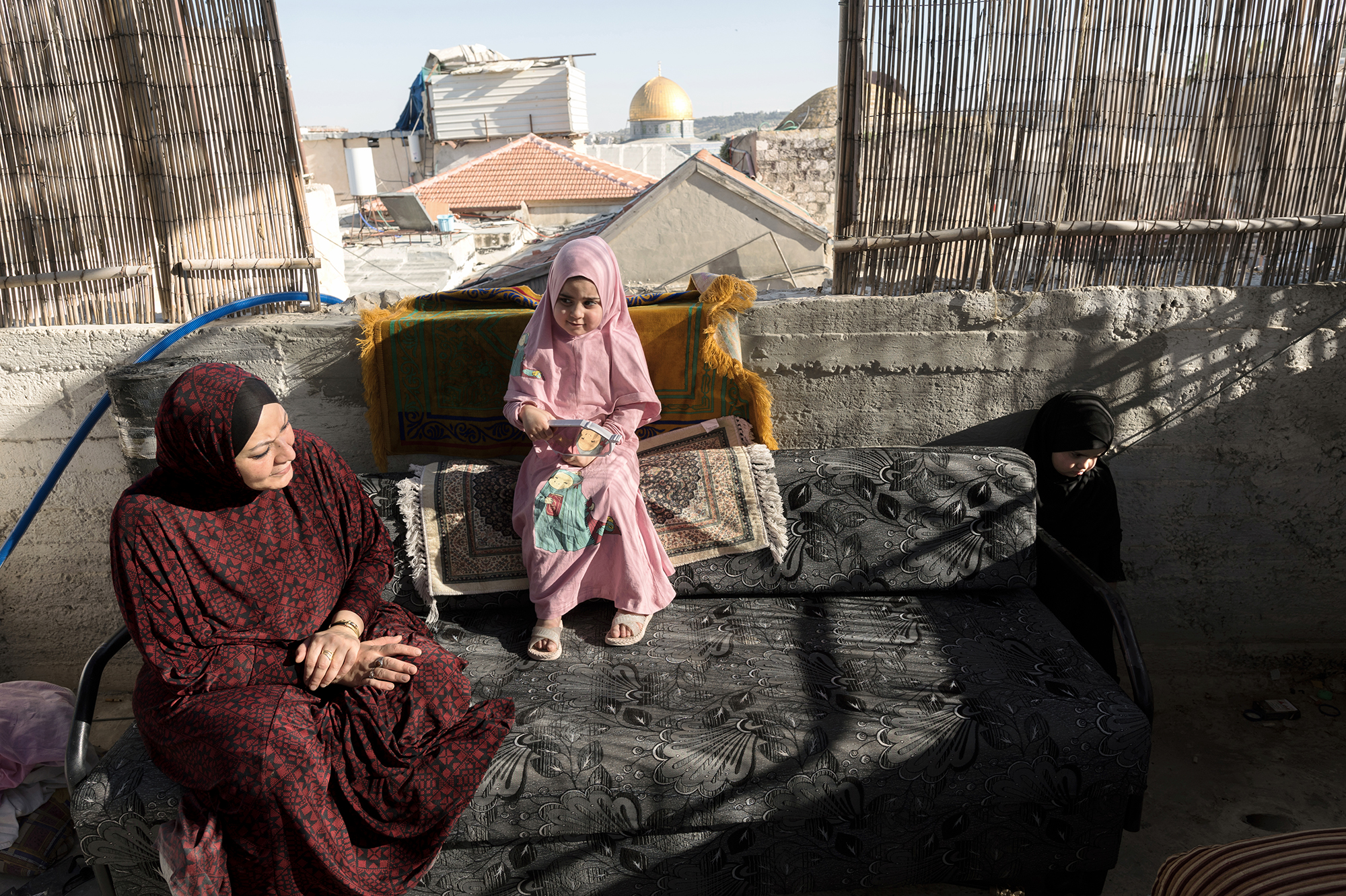 mother and daughter sitting on a sofa on a roof in Jerusalem.