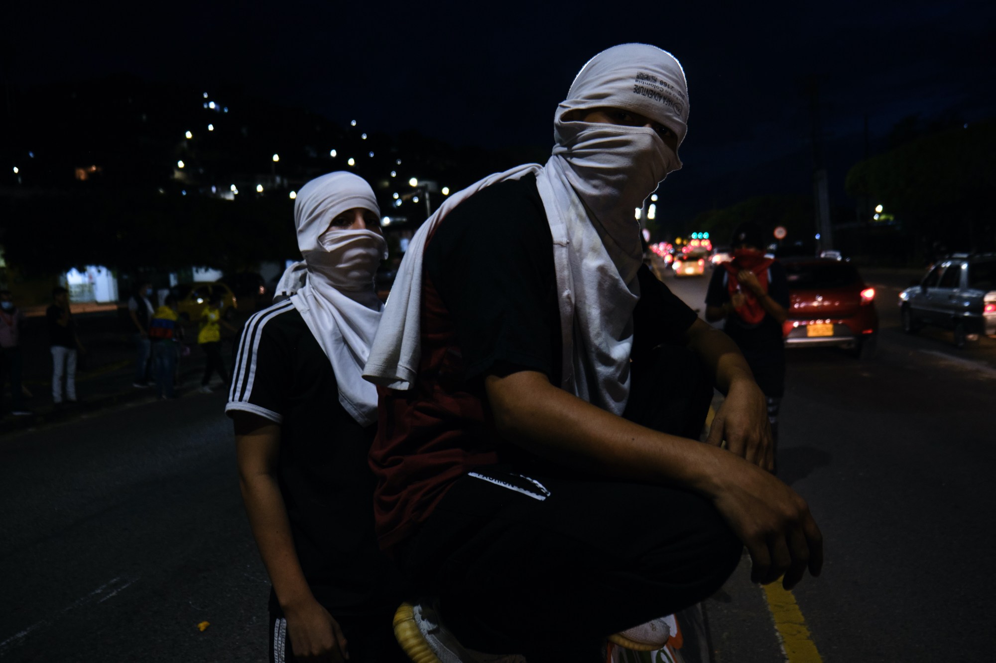 two protestors covering their faces with t-shirts wrapped around their head