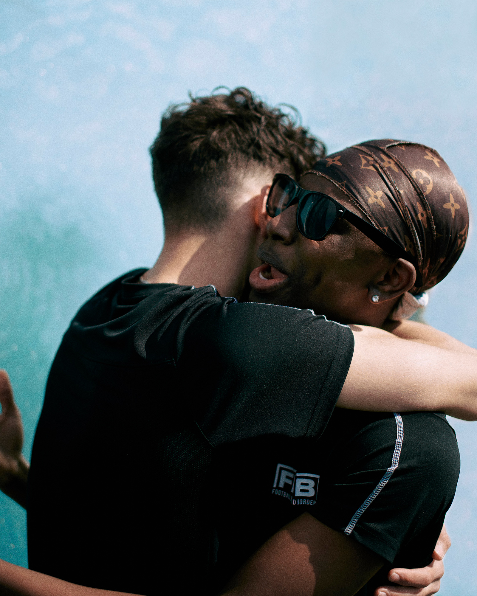 Two boys hugging against a blue background