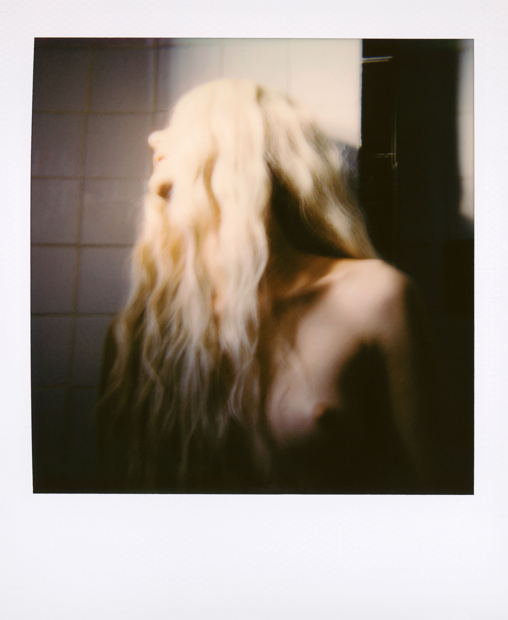 Colour polaroid of a model with long platinum hair looking into the sunlight