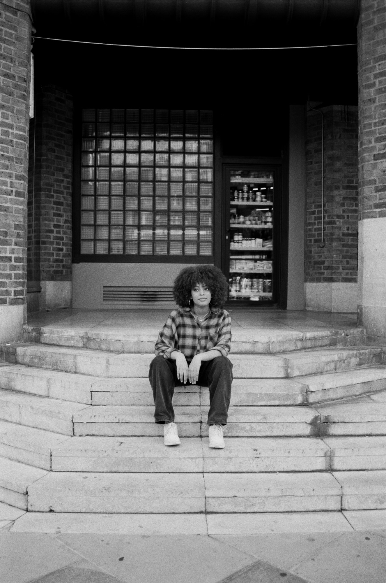 activist christina adane sits on some steps near a public foodbank