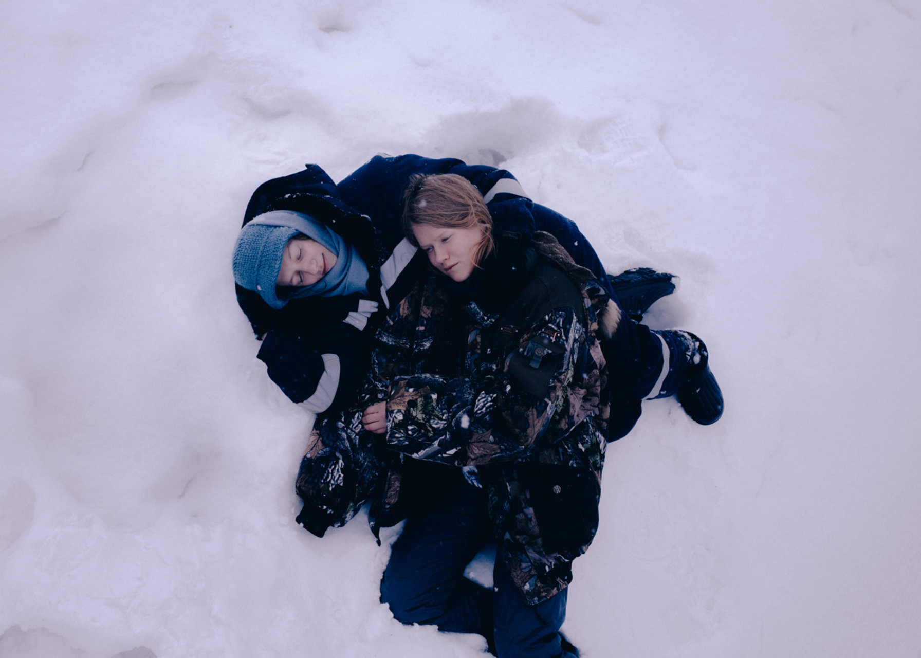 two people lying on top of each other in the snow