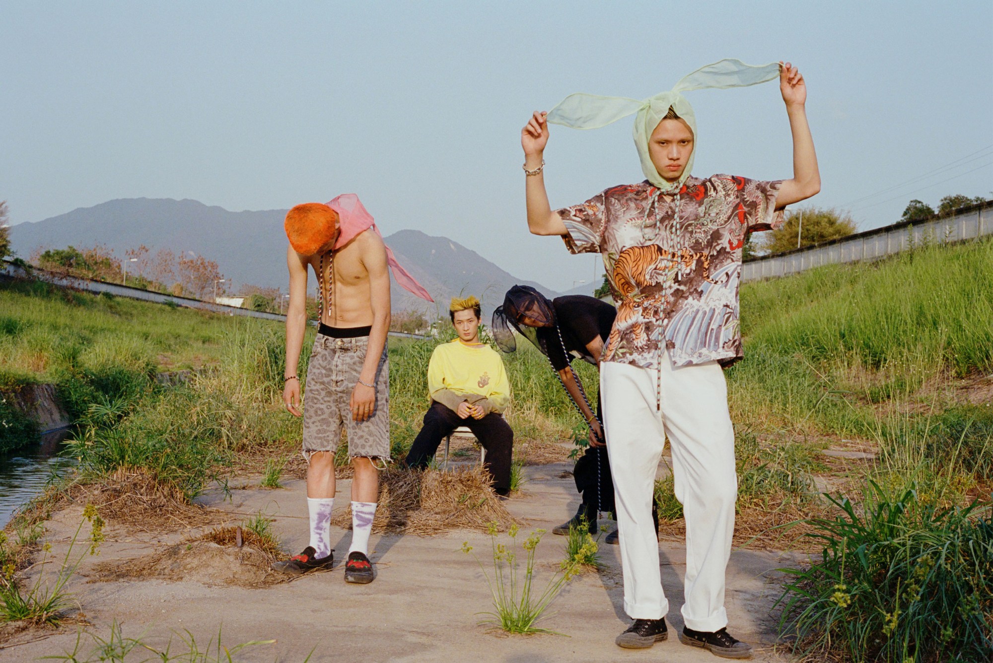 four young men wearing tulle bunny ears stand by a river in rural Hong Kong