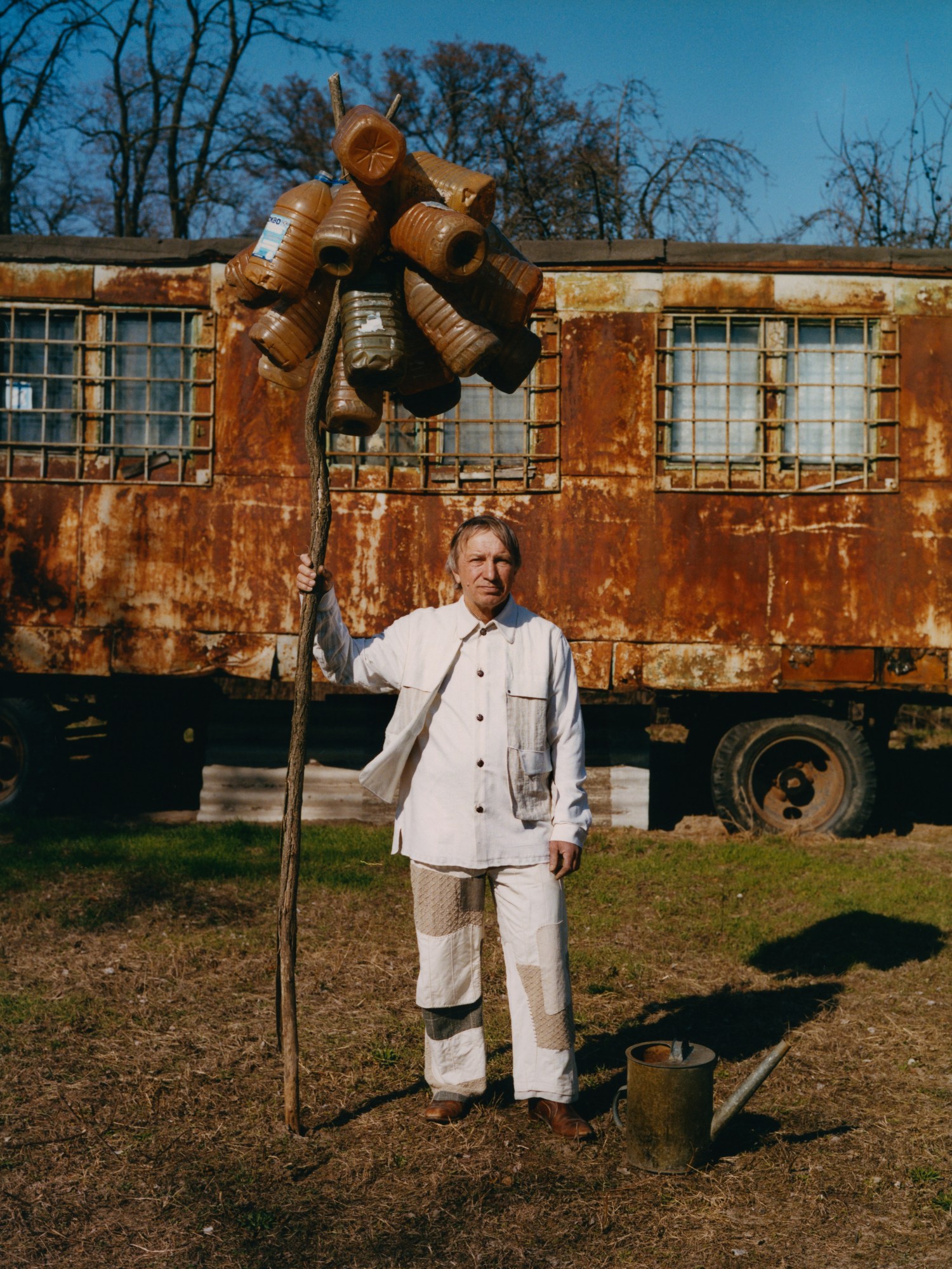 a man holding a stick with plastic bottles attached to the top