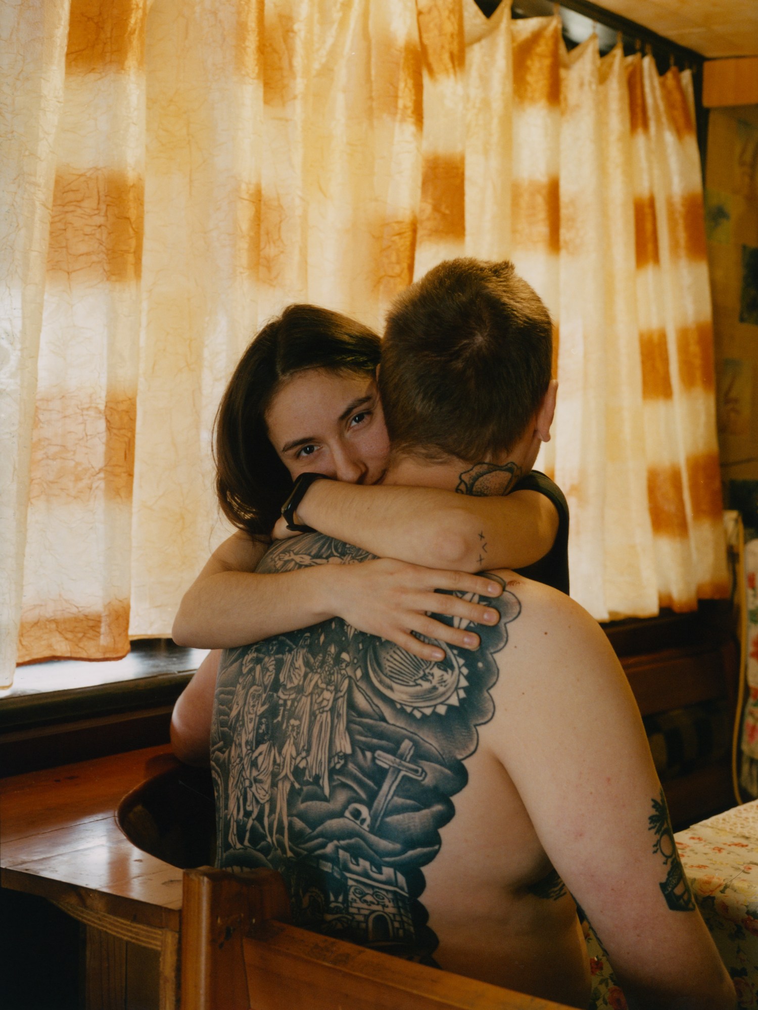 a woman hugs a man with a large tattoo on his back