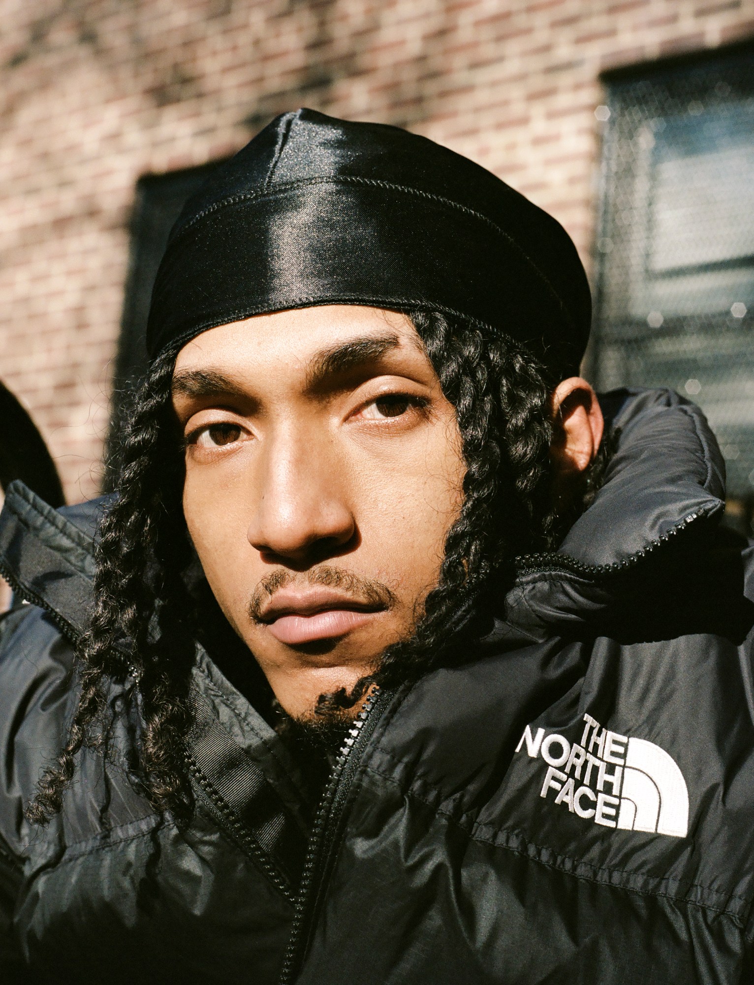 a close up of a man with braids framing his face by kadar small