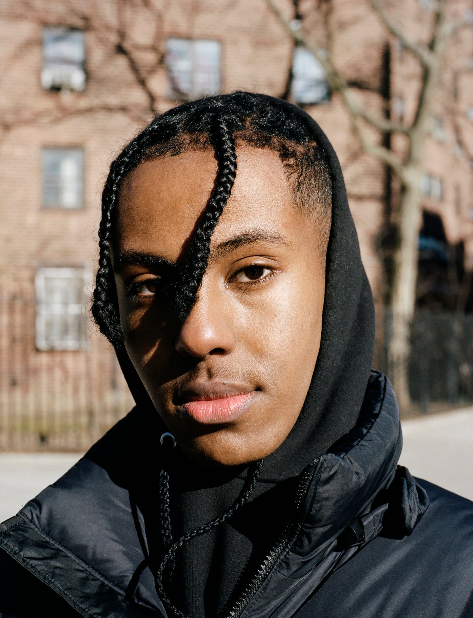 a boy staring into the camera with braids swept across his face by kadar small