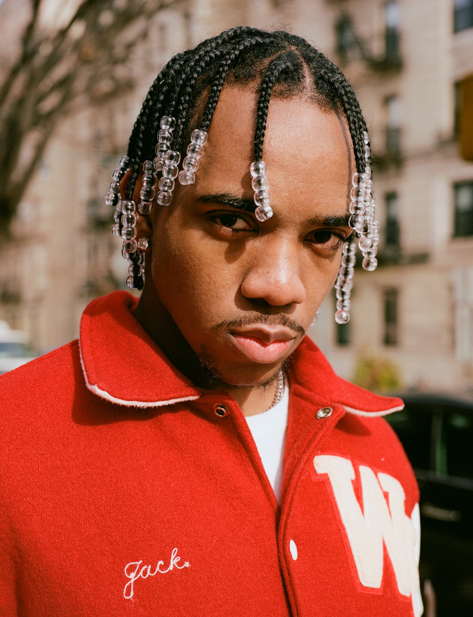 a guy with beaded braids wearing a red letterman jacket by kadar small