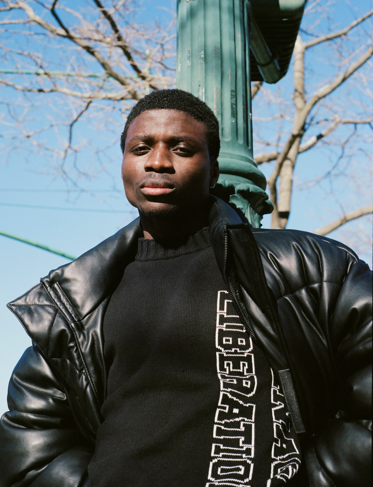 a guy standing against a streetlight with his jacket pulled open by kadar small