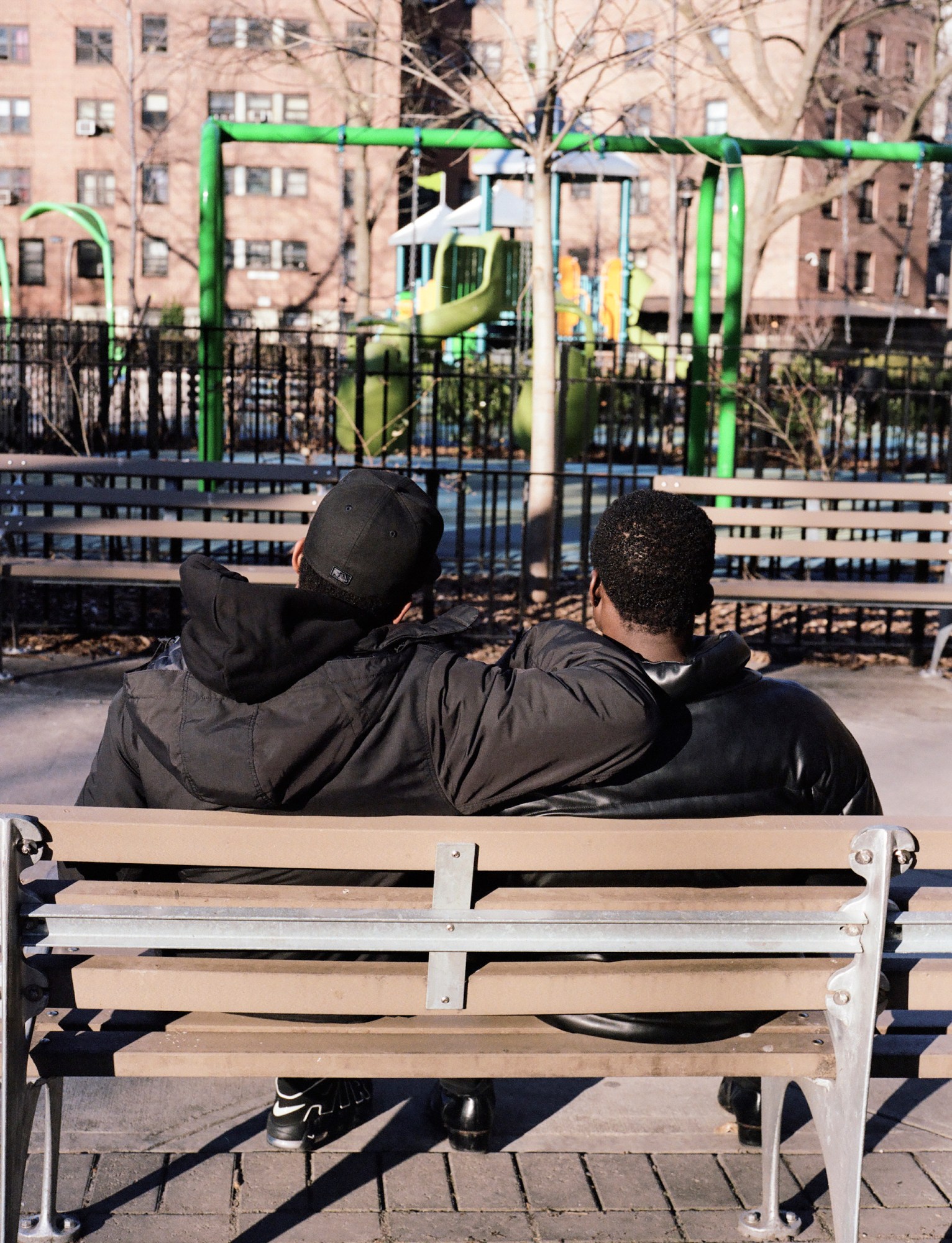 two men embracing on a park bench in nyc by kadar small