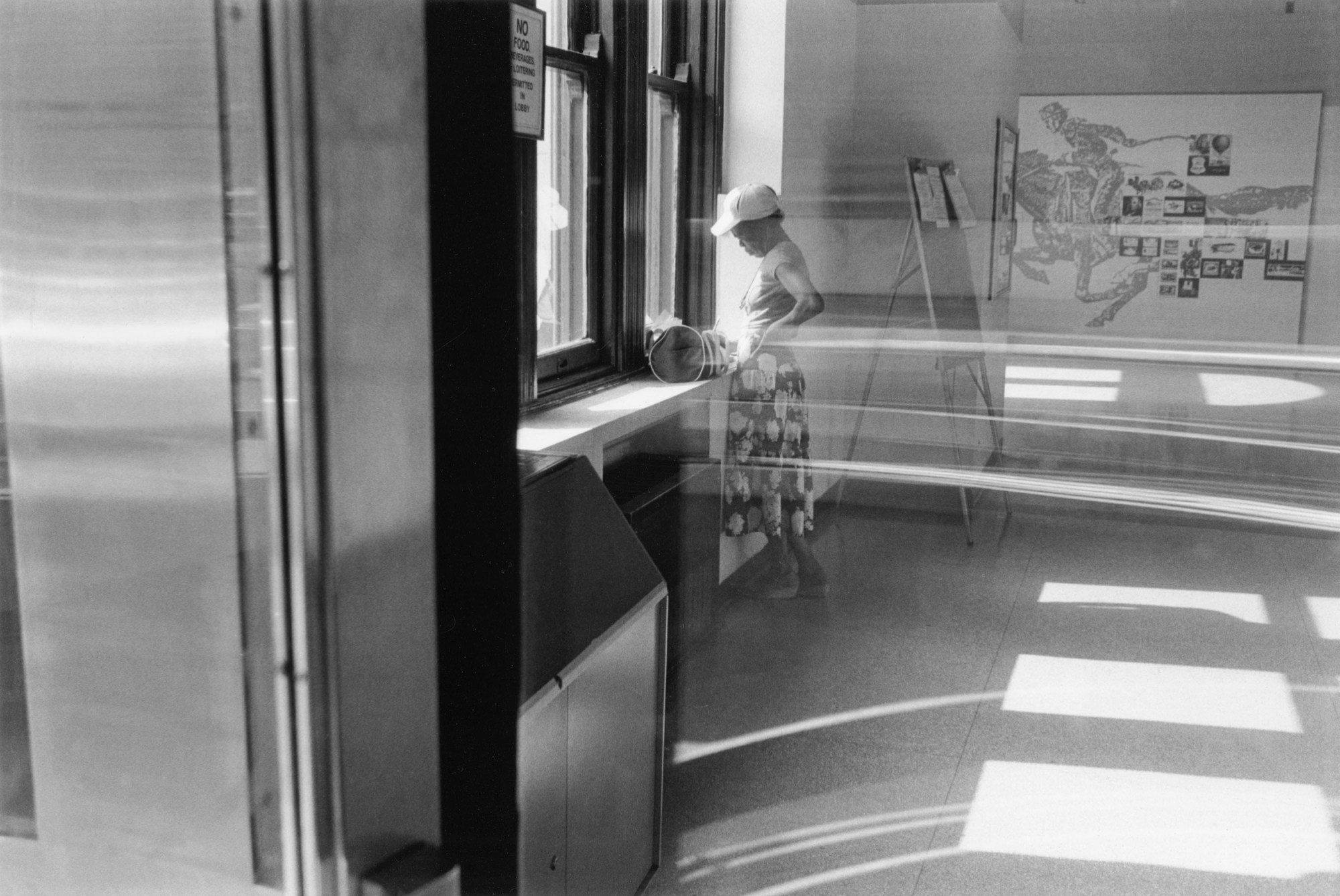 a woman inside a post office is photographed through the window