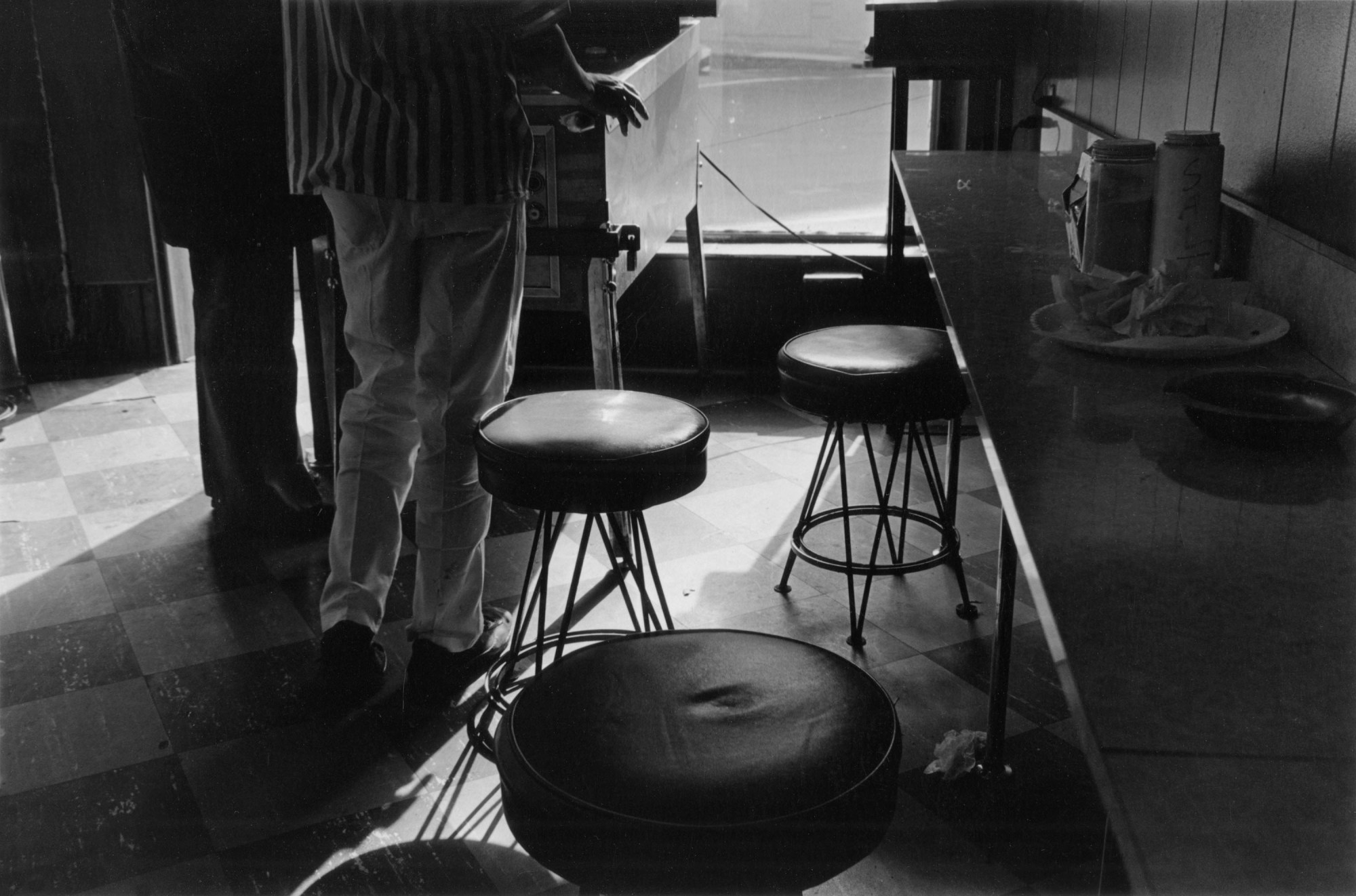 a handful of stools and a man leading over an arcade game