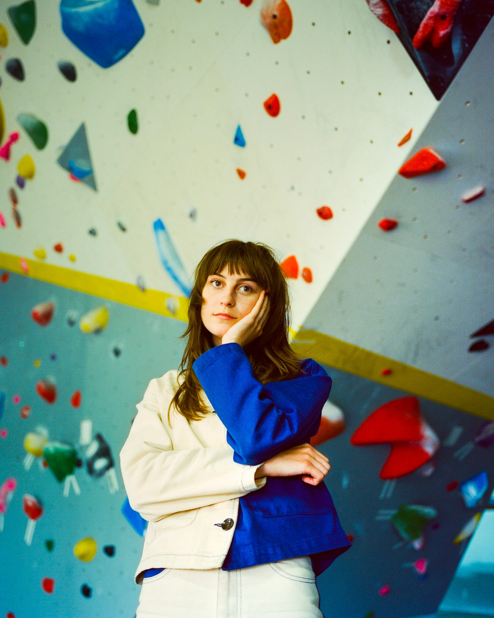 faye webster posing in front of a rock climbing wall