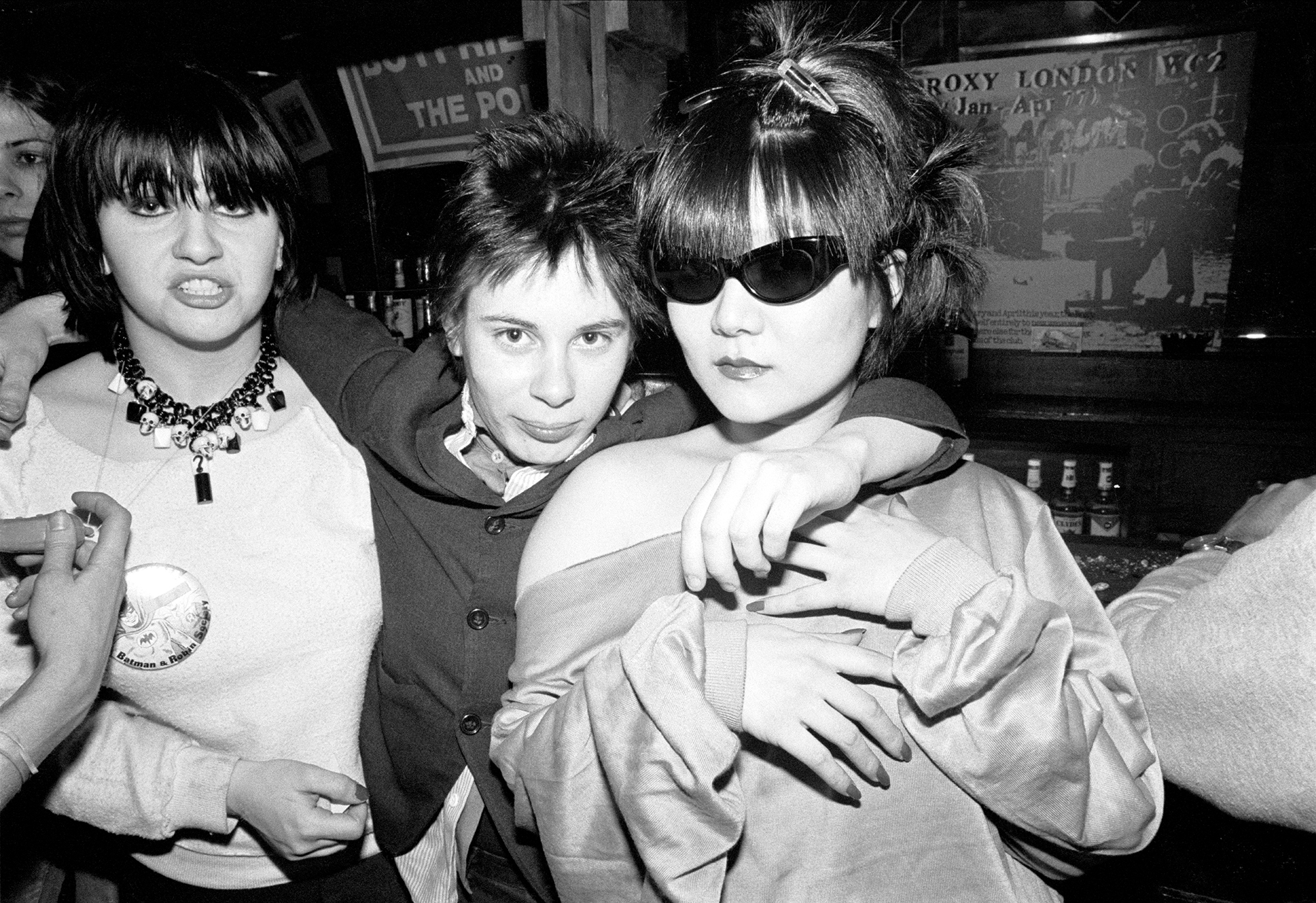 three people inside a bar, one of whom is wearing sunglasses