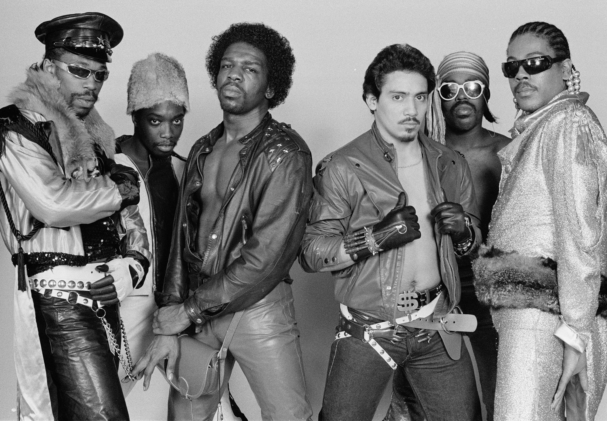 a hip hop group wearing leather jackets and posing in a studio