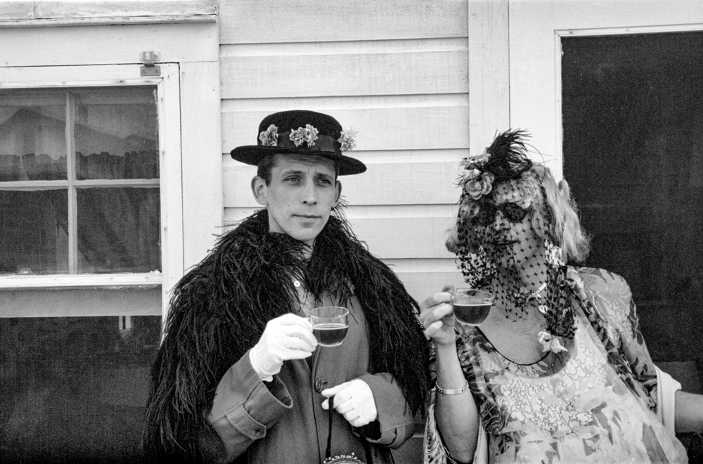 two party guests wearing costumes and holding cups of tea