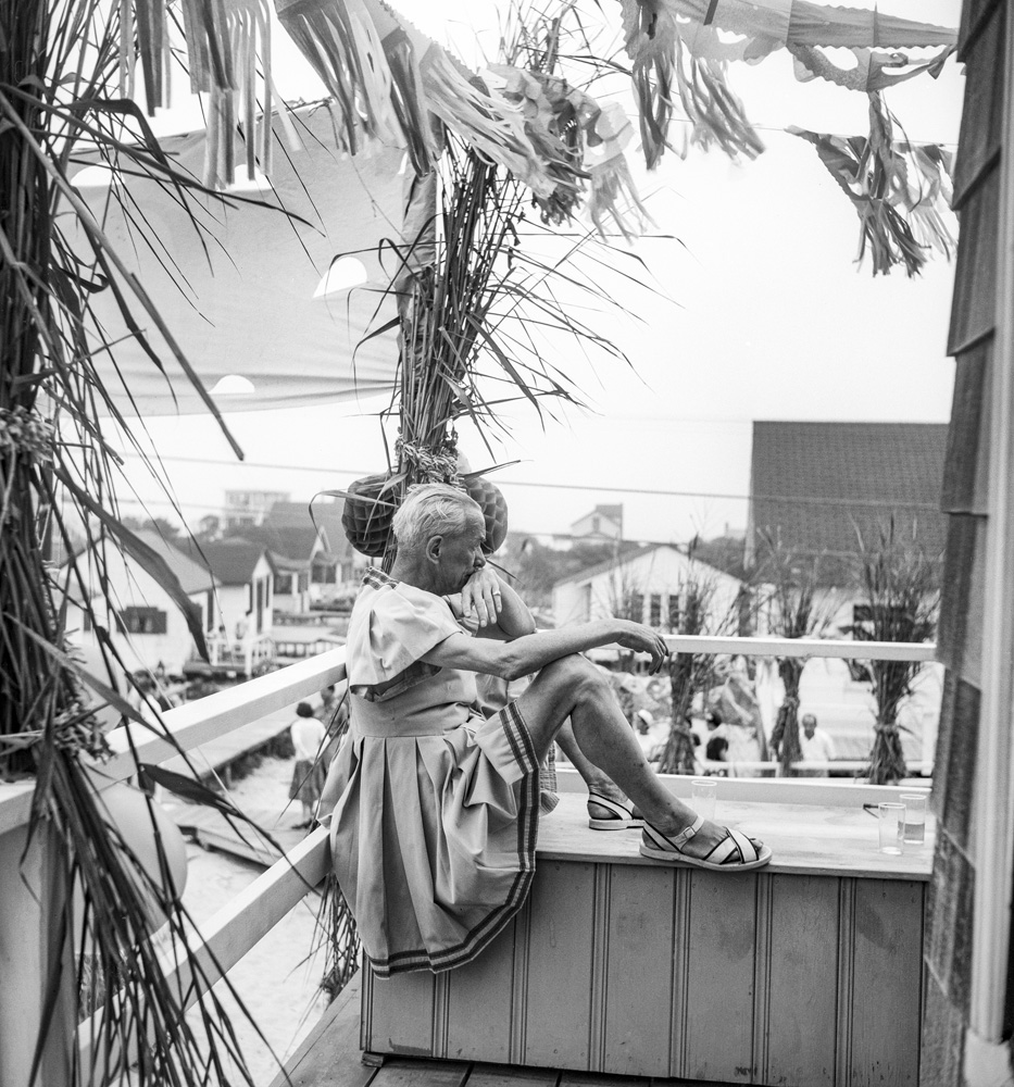 a man in a dress and sandals sitting on a porch