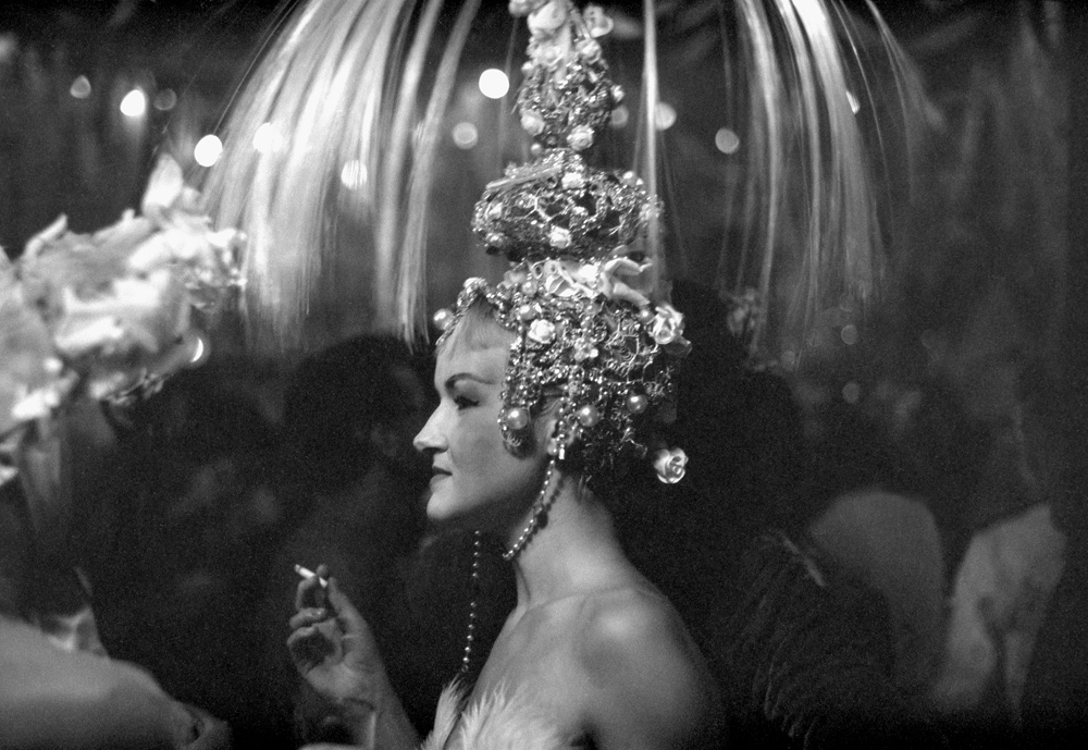 a woman wearing a crystal headdress and holding a cigarette