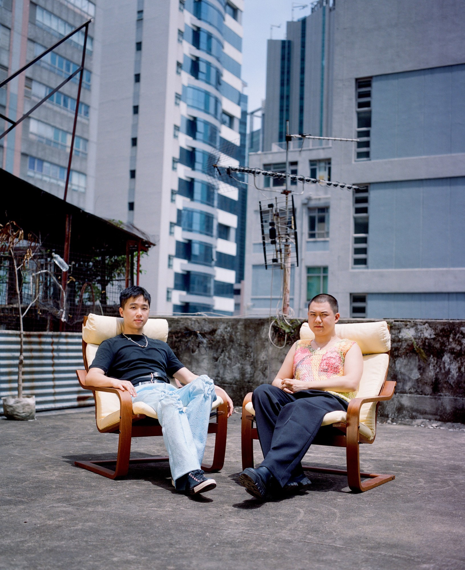 derek cheng and alex po sitting in chairs on a hong kong rooftop