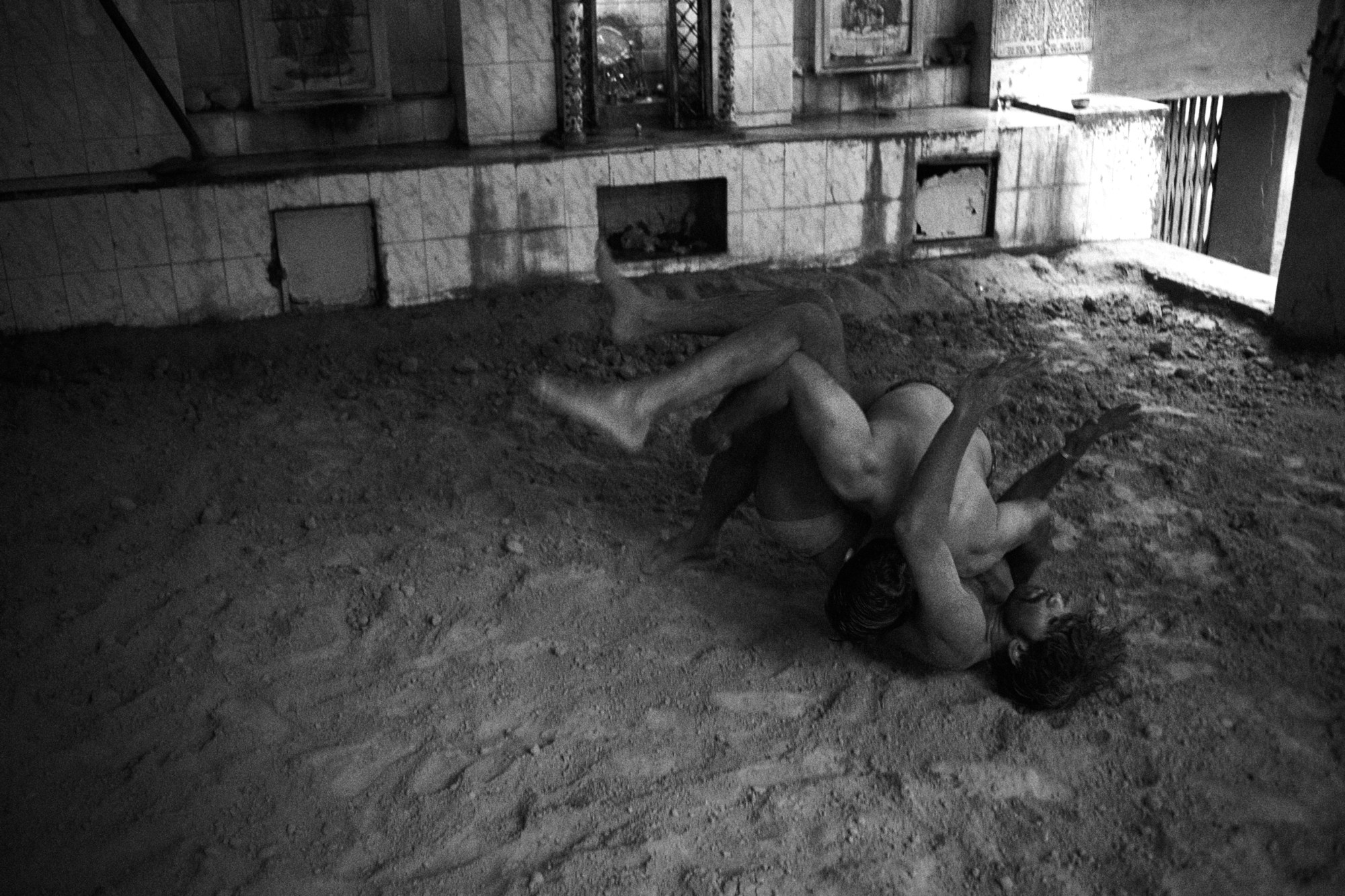 two men wrestle on a sand floor