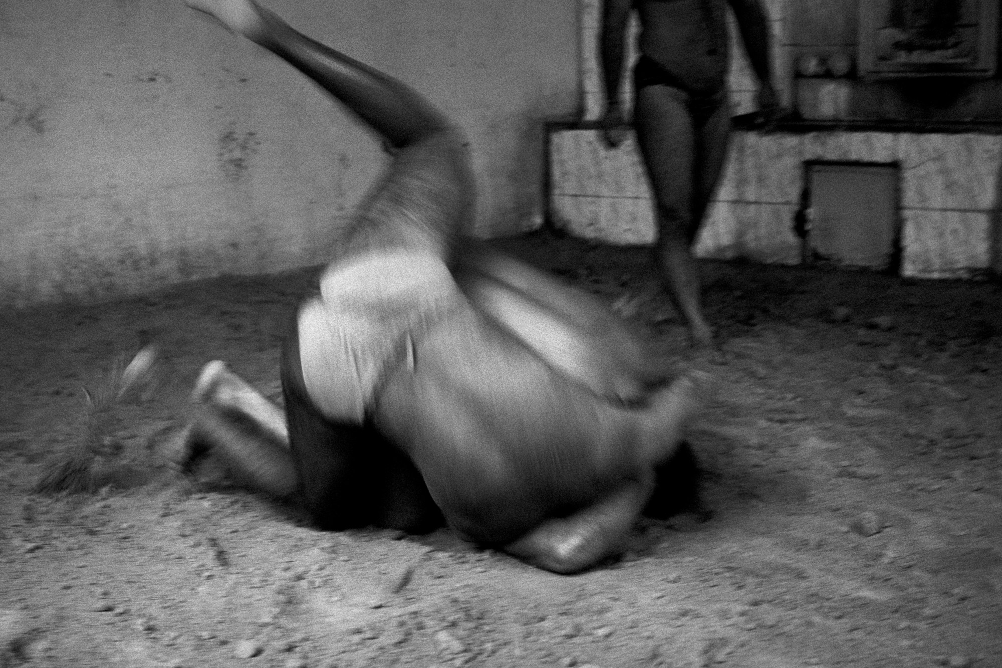 two men wrestling on the floor while another overlooks